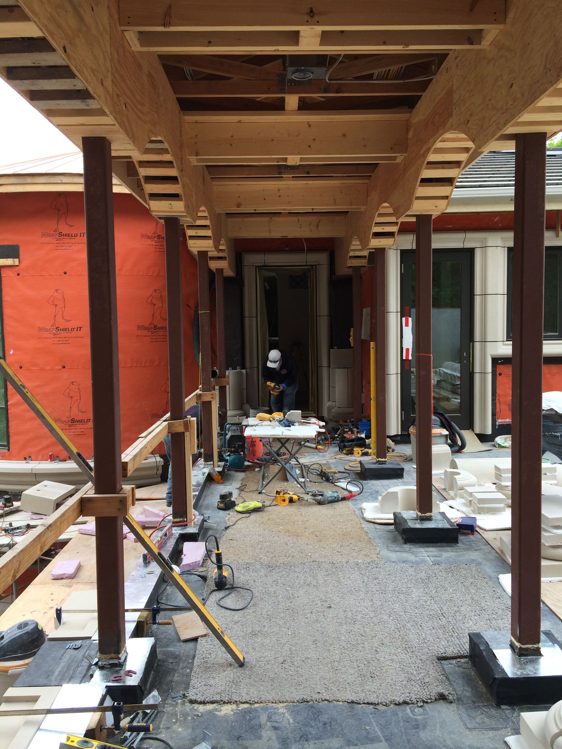Construction corridor with exposed wooden beams, red walls, and scattered tools and debris on the floor.
