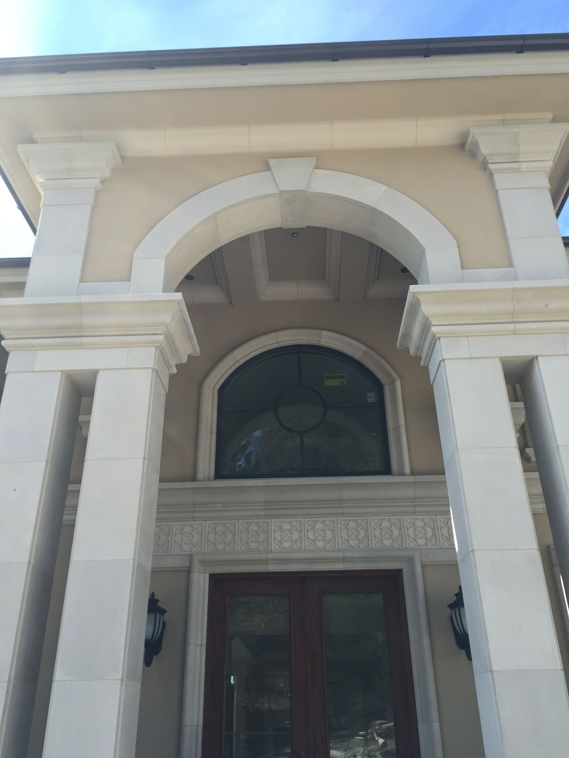 Ornate cream-colored building entrance with arched doorway and decorative columns