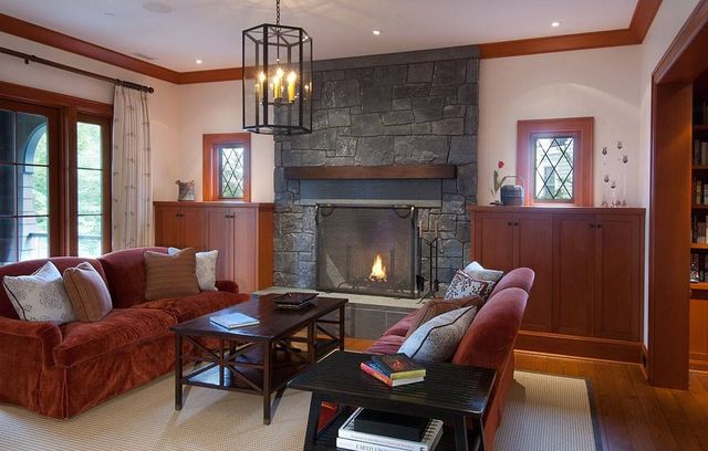 Cozy living room with a stone fireplace, red sofas, wood trim, and a hanging lantern light.