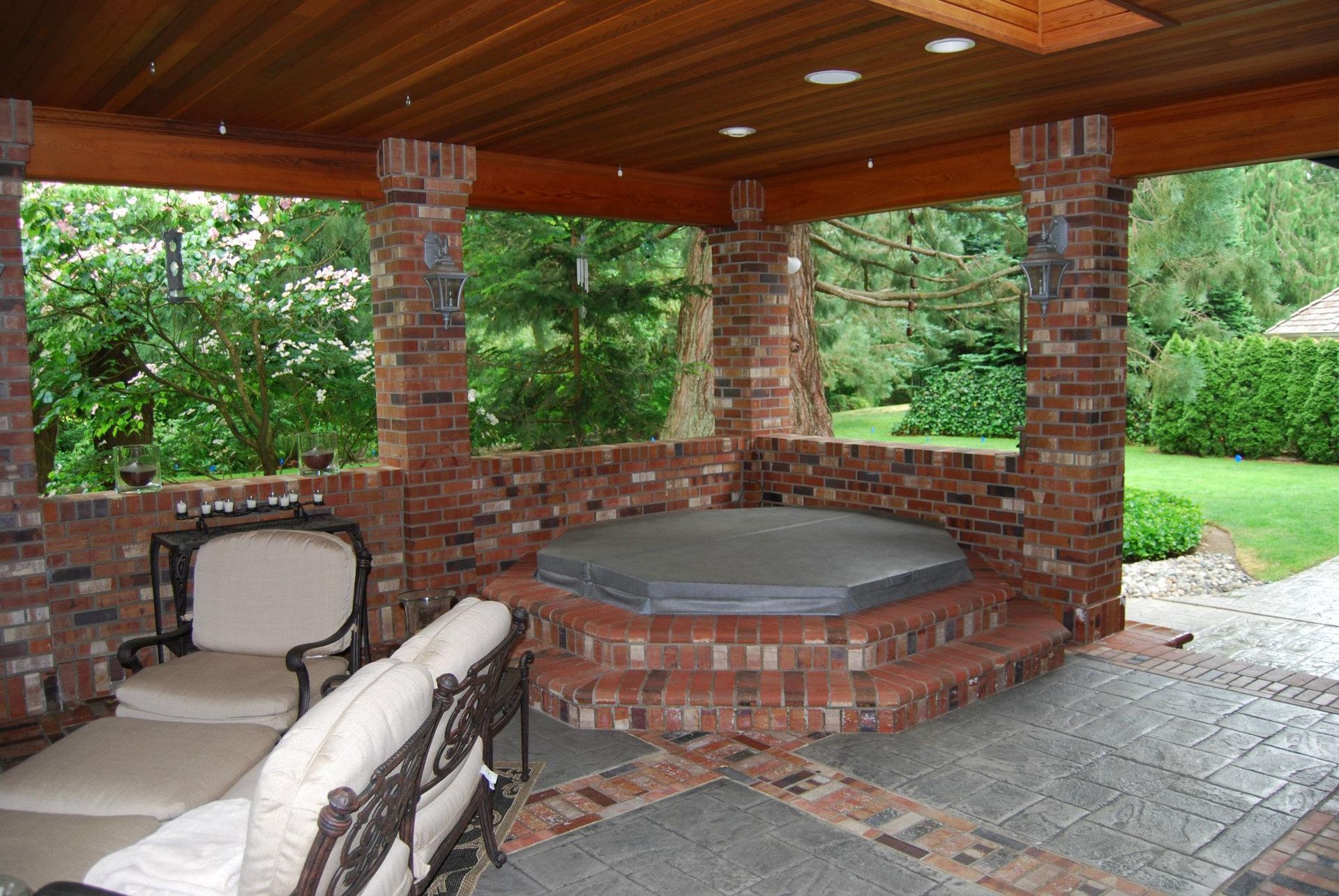Brick outdoor patio with a covered hot tub, seating, and a wood-paneled ceiling