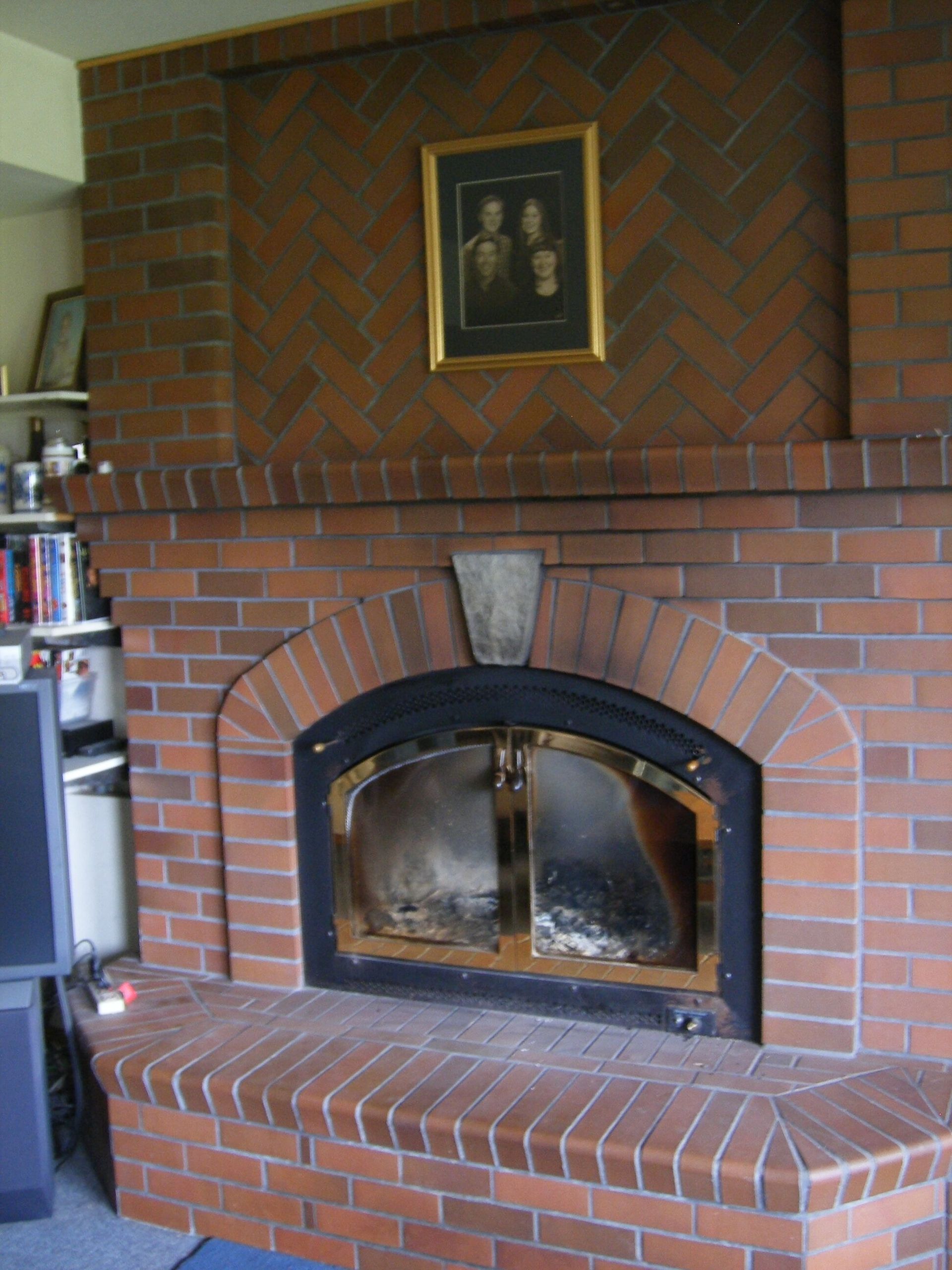 Brick fireplace with black-framed glass doors and a framed picture above it