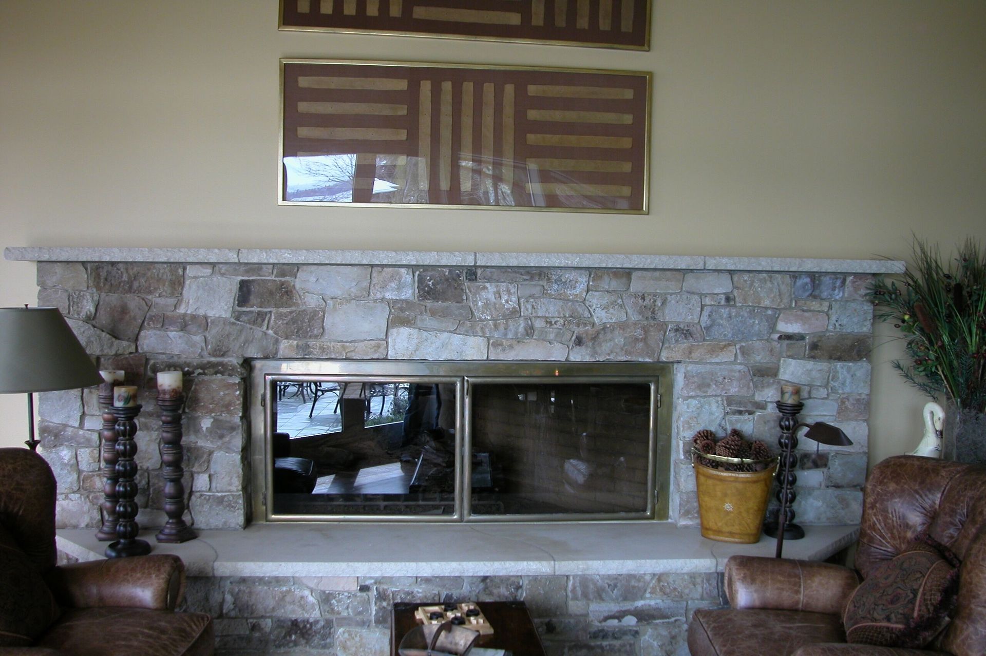 Living room with a stone fireplace, mirror above, and brown chairs on either side