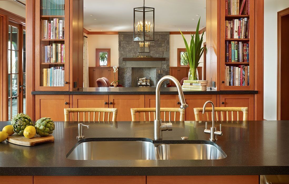 Modern kitchen with stainless sink, dark island countertop, wood cabinets, and fruit on the counter