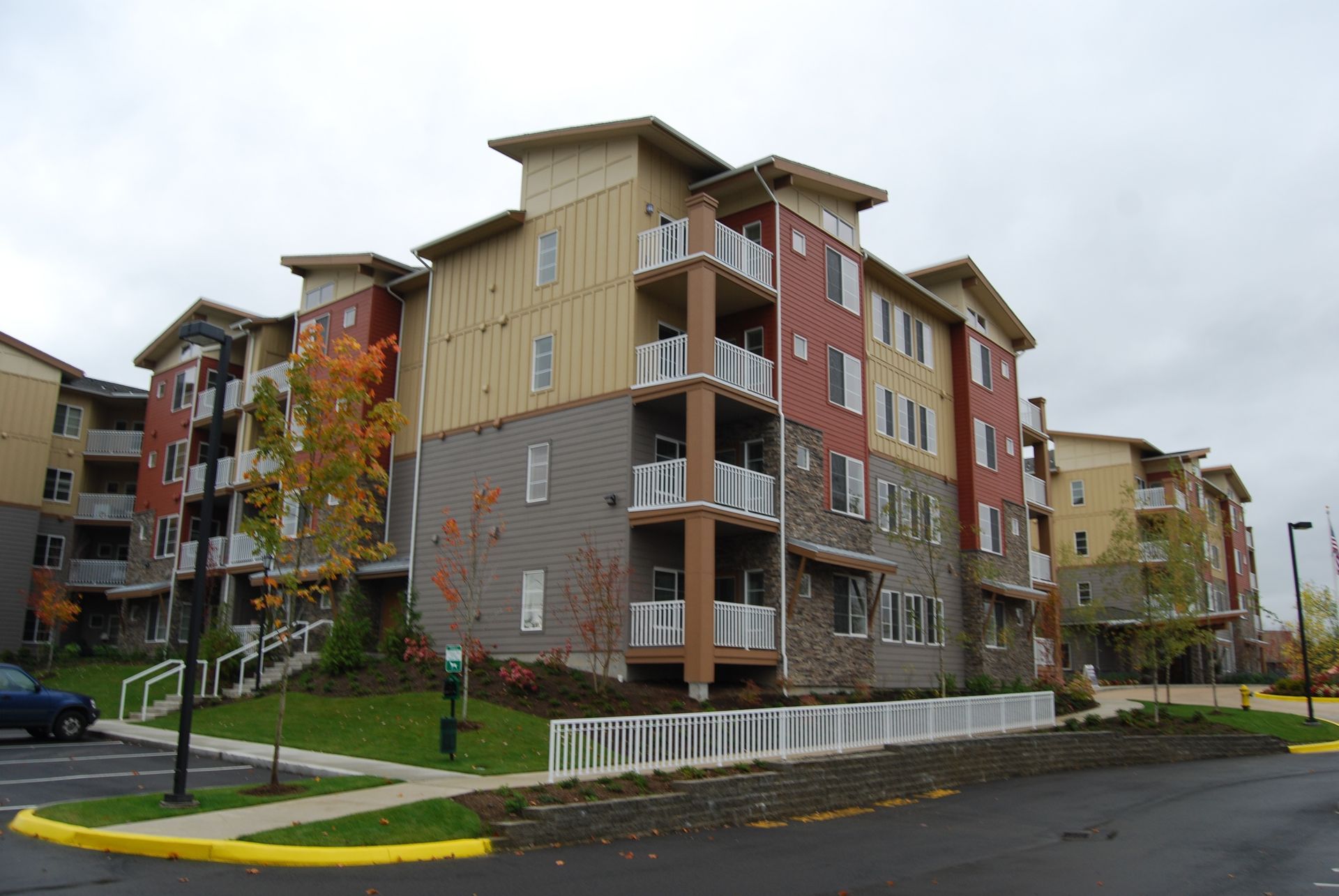 Modern apartment building with balconies on a street corner, under an overcast sky
