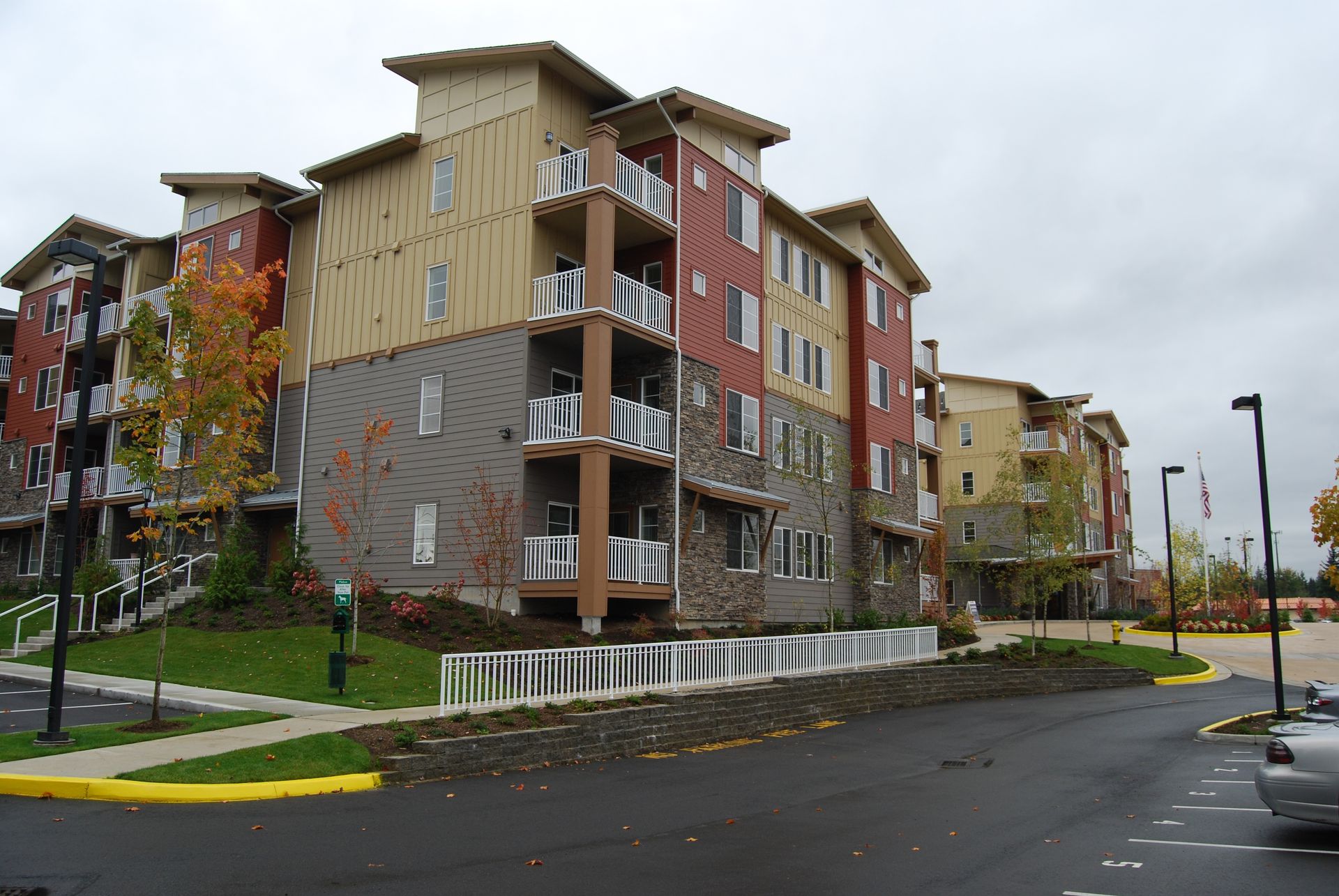 Apartment buildings beside a wet street with fall trees on an overcast day