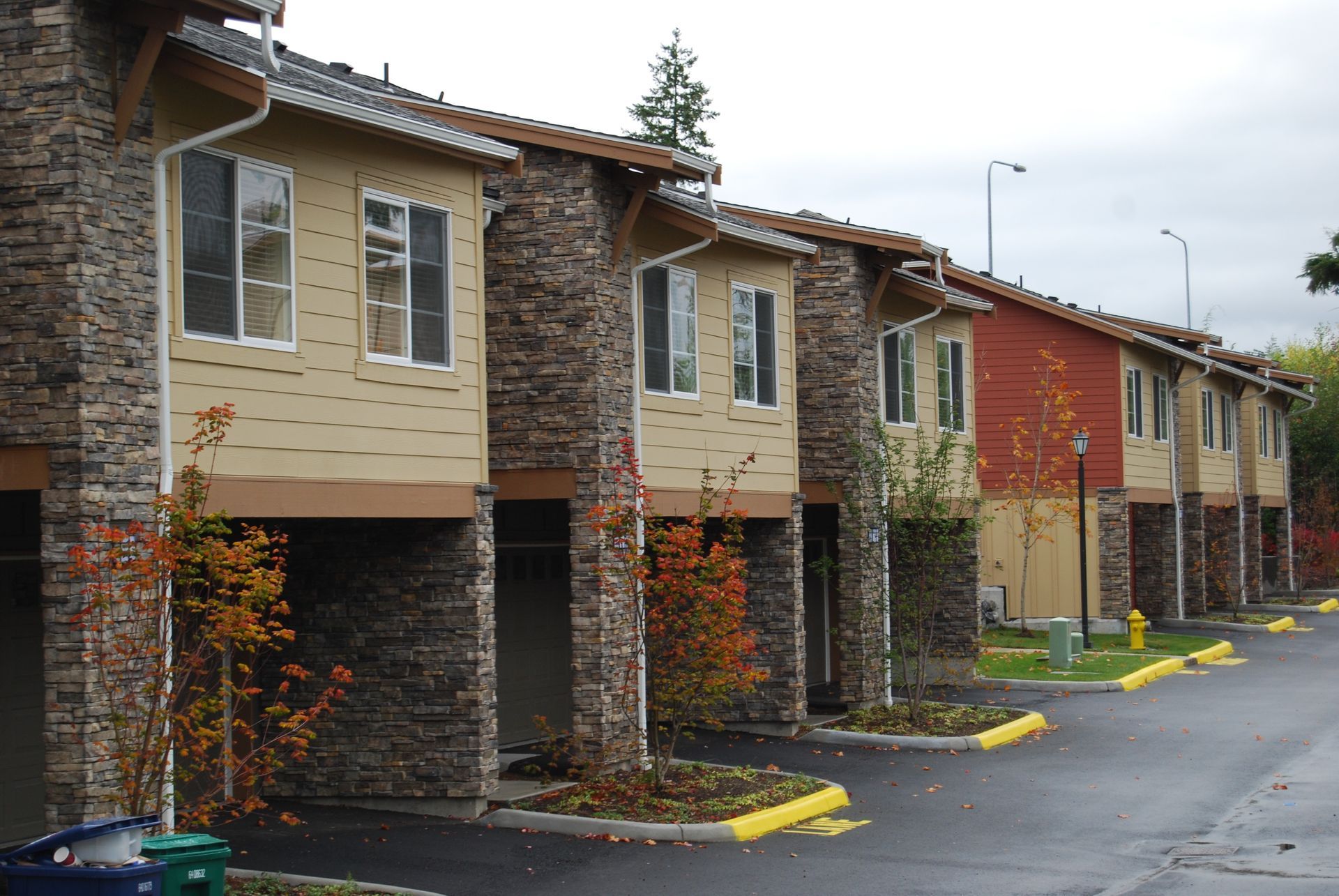 Row of beige and red townhouse apartments with covered carports on a wet driveway