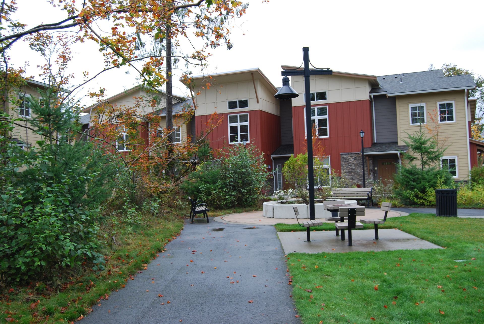 Courtyard path with picnic tables, trees, and red-and-beige apartment buildings