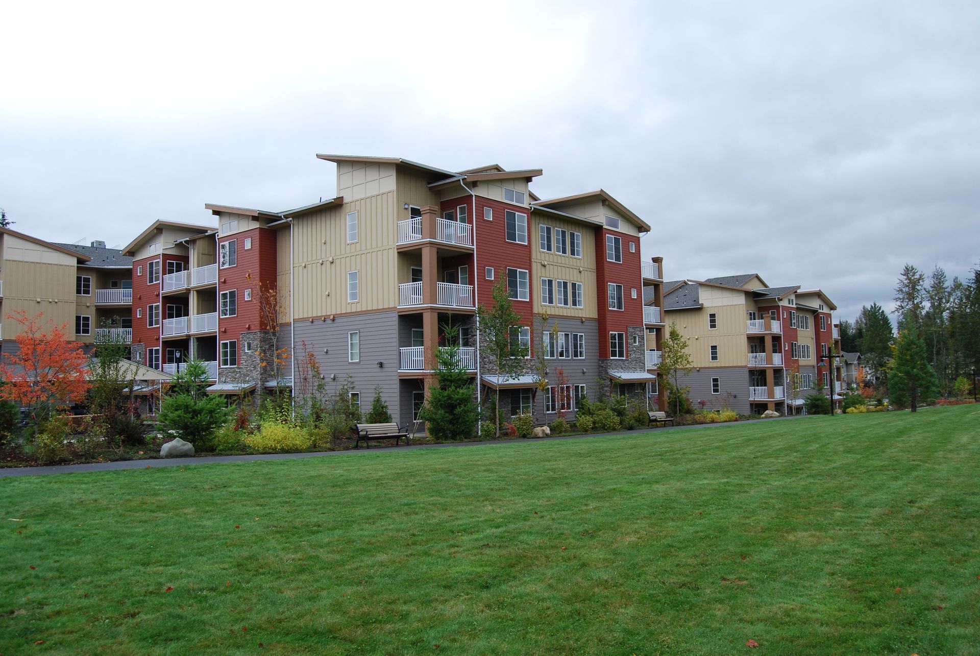 Apartment buildings beside a green lawn under a cloudy sky