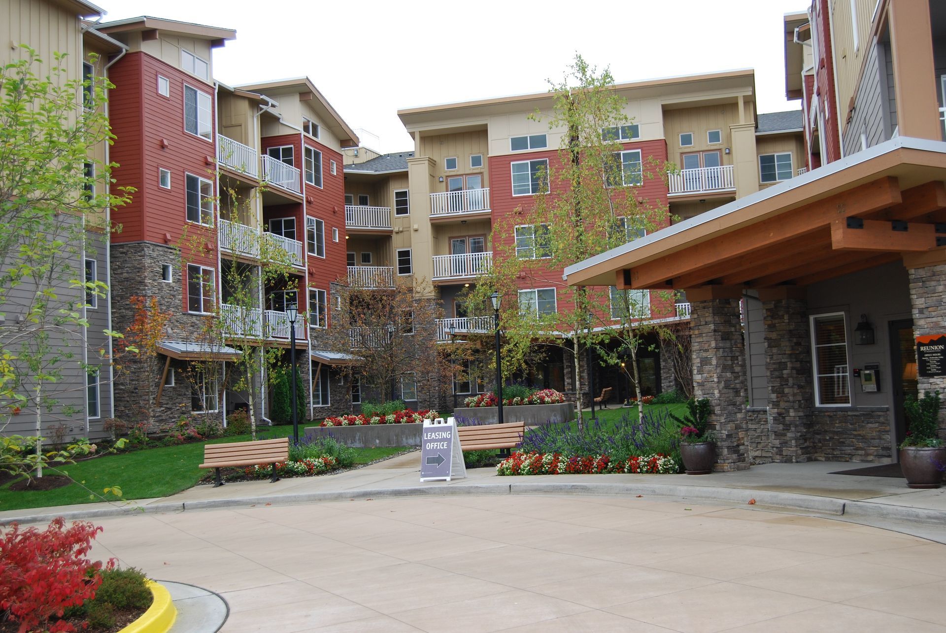 Apartment courtyard with brick and stone buildings, flower beds, and a paved walkway