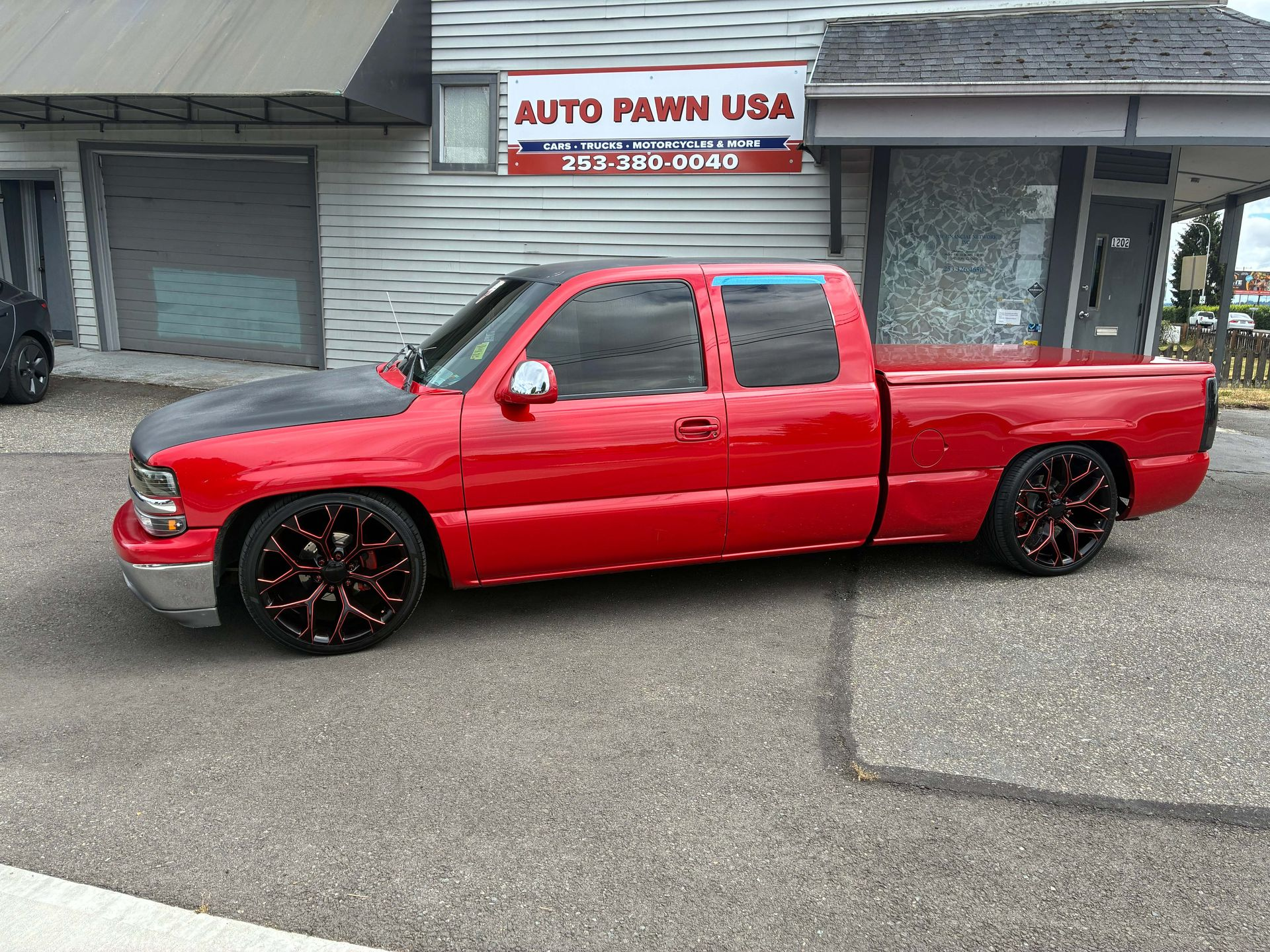 Red extended cab pickup truck with custom wheels outside the Auto Pawn USA shop in Auburn WA