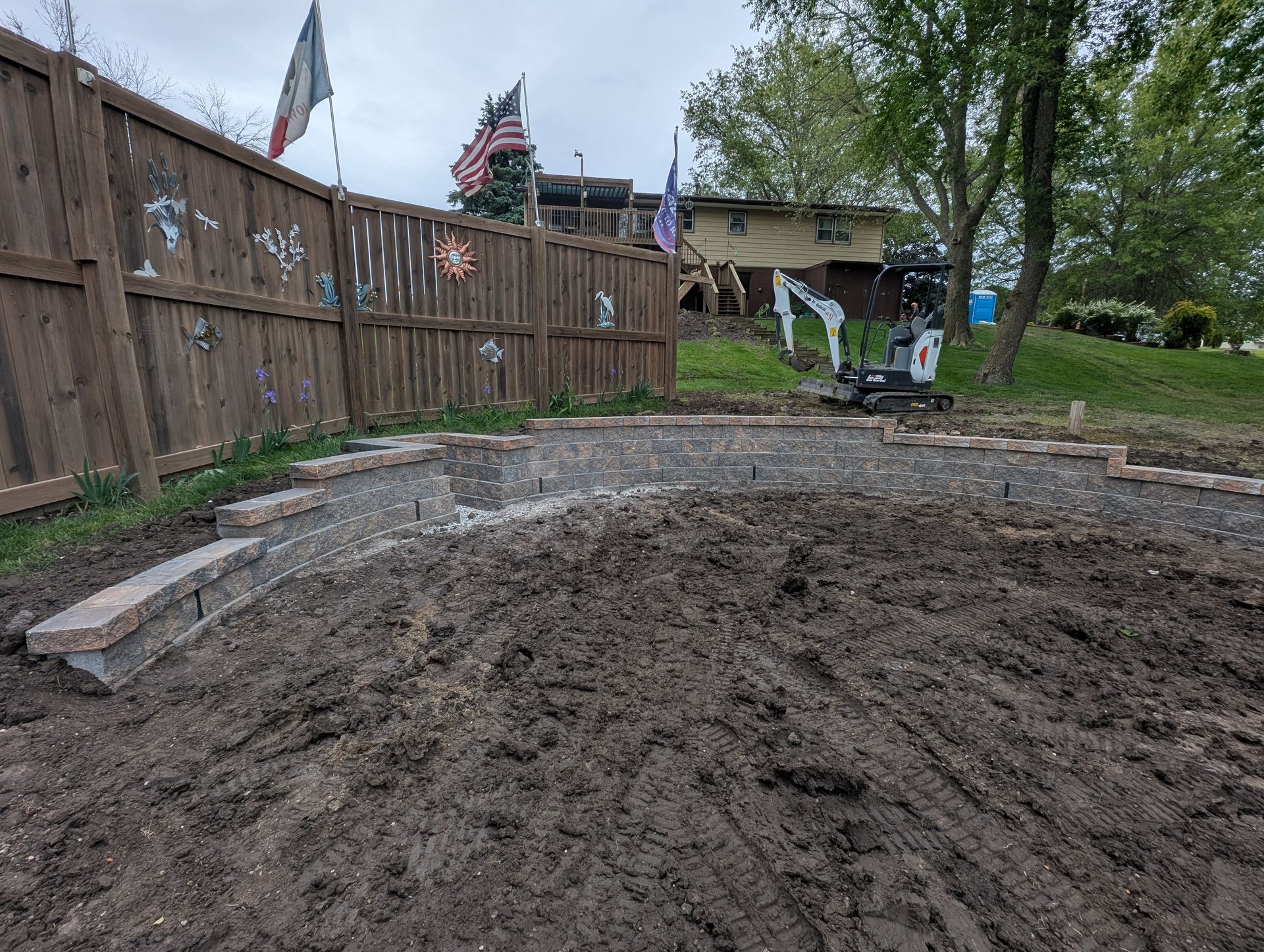 Newly built curved stone retaining wall, part of a residential hardscaping project.] [Provided by Co
