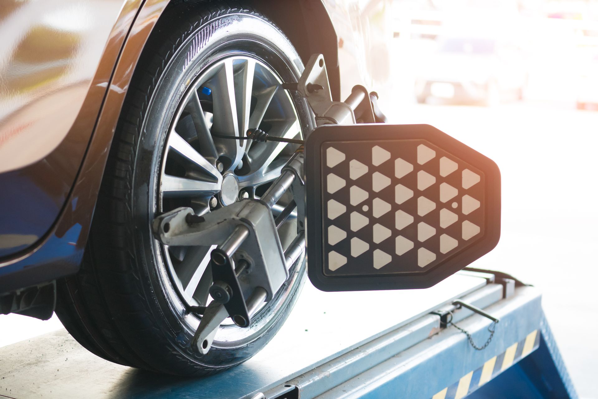 Car wheel on a wheel alignment machine with a sensor attached in a bright auto shop