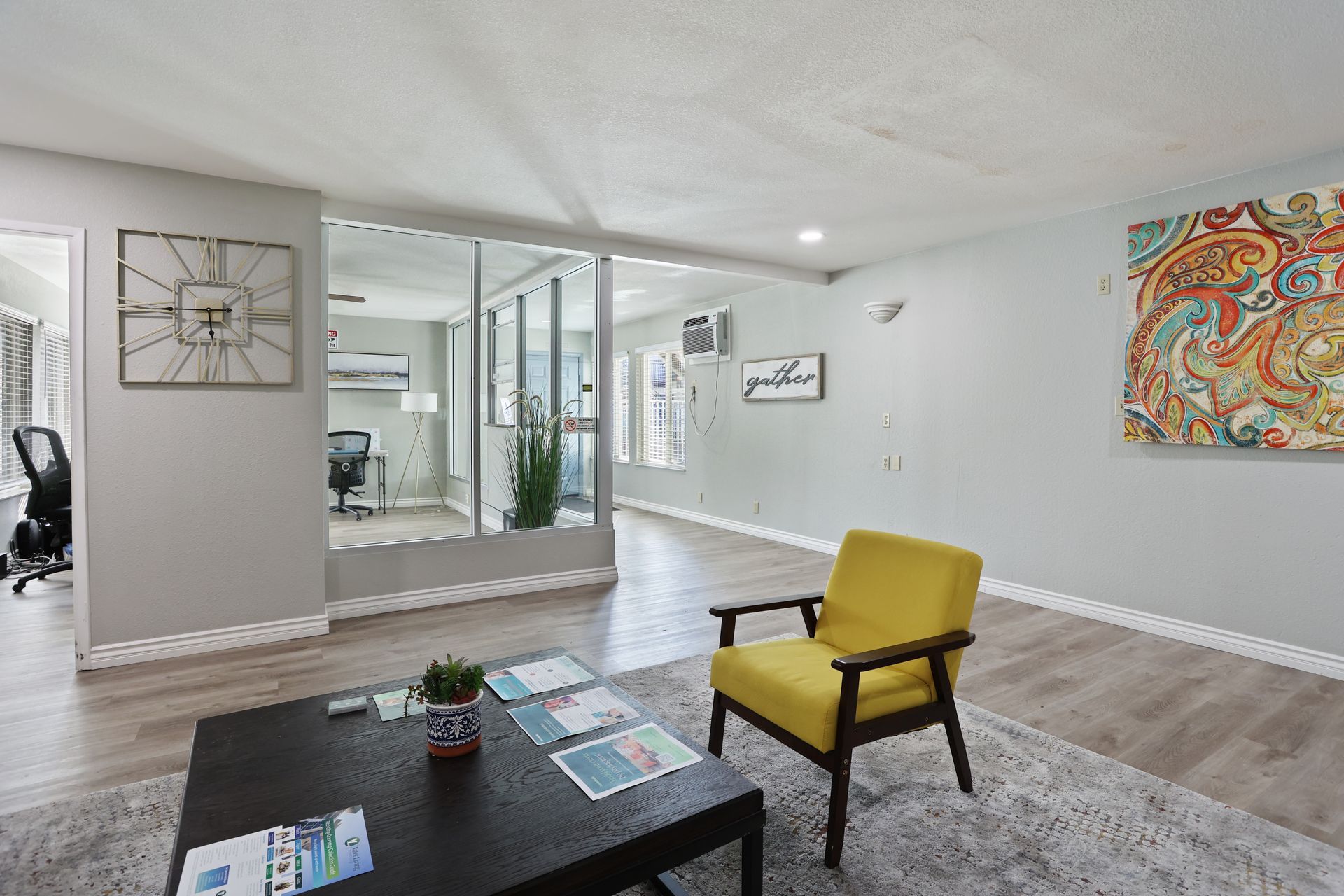 Bright open living room with blue chair, dining area, hallway, and light wood floors