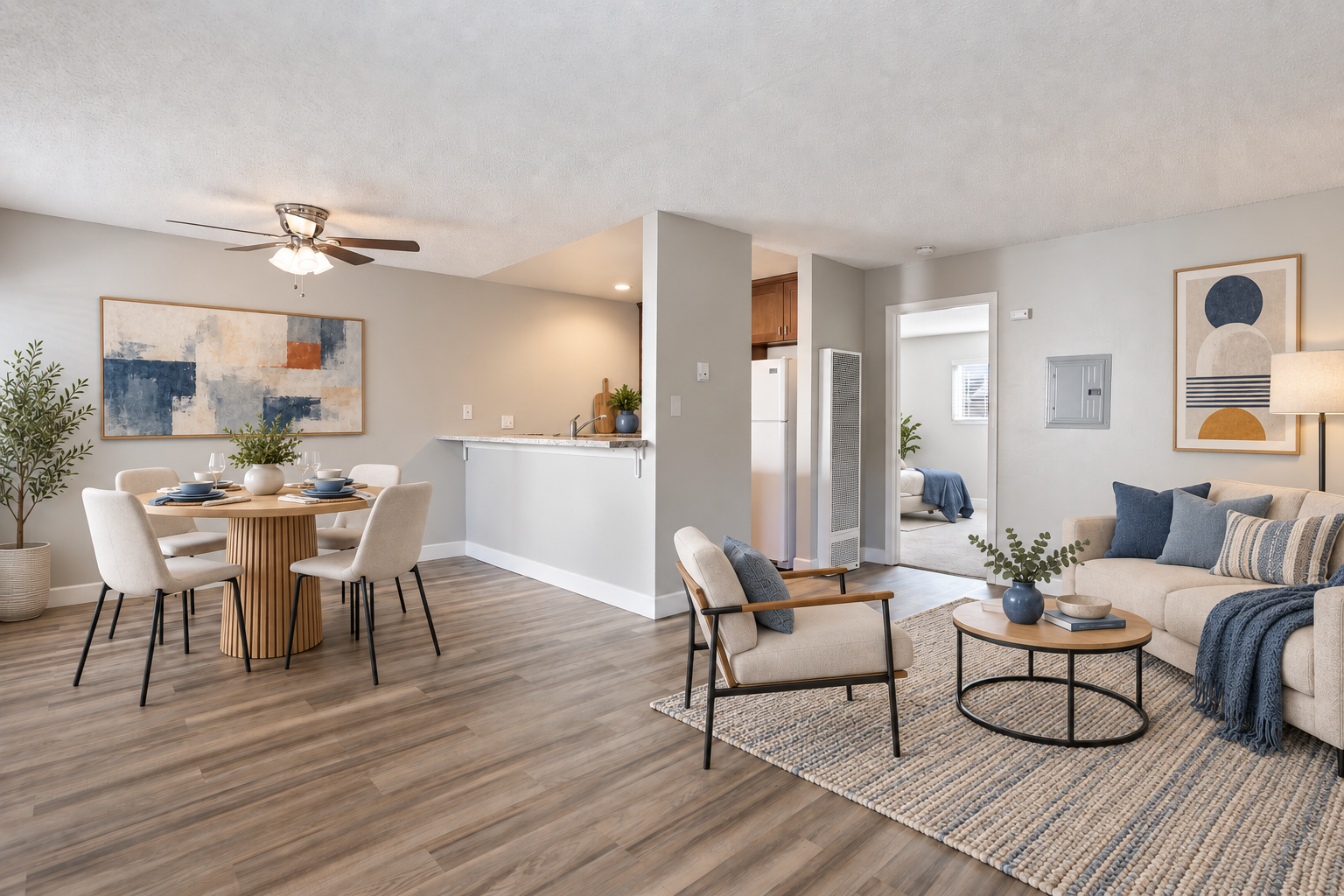 Open-concept living and dining room with light wood floors, neutral decor, and a sofa with round coffee table.