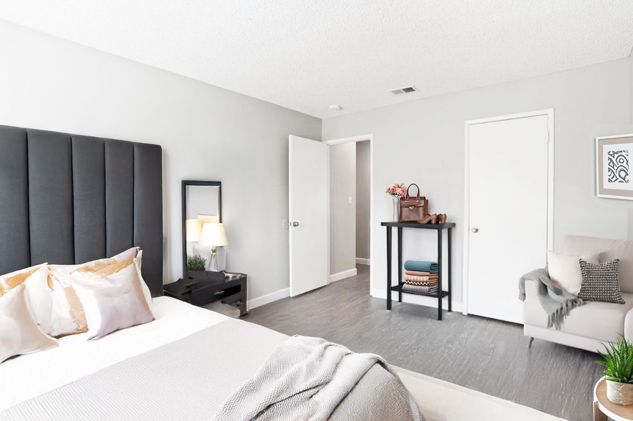 Bright bedroom with white walls, bed, mirror, closet doors, and a small desk by the window.