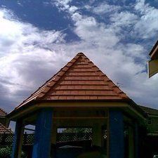 A gazebo with a red tiled roof and a blue curtain.