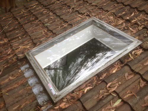 A skylight is sitting on top of a tiled roof.