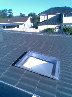 A roof with a skylight on it and a house in the background