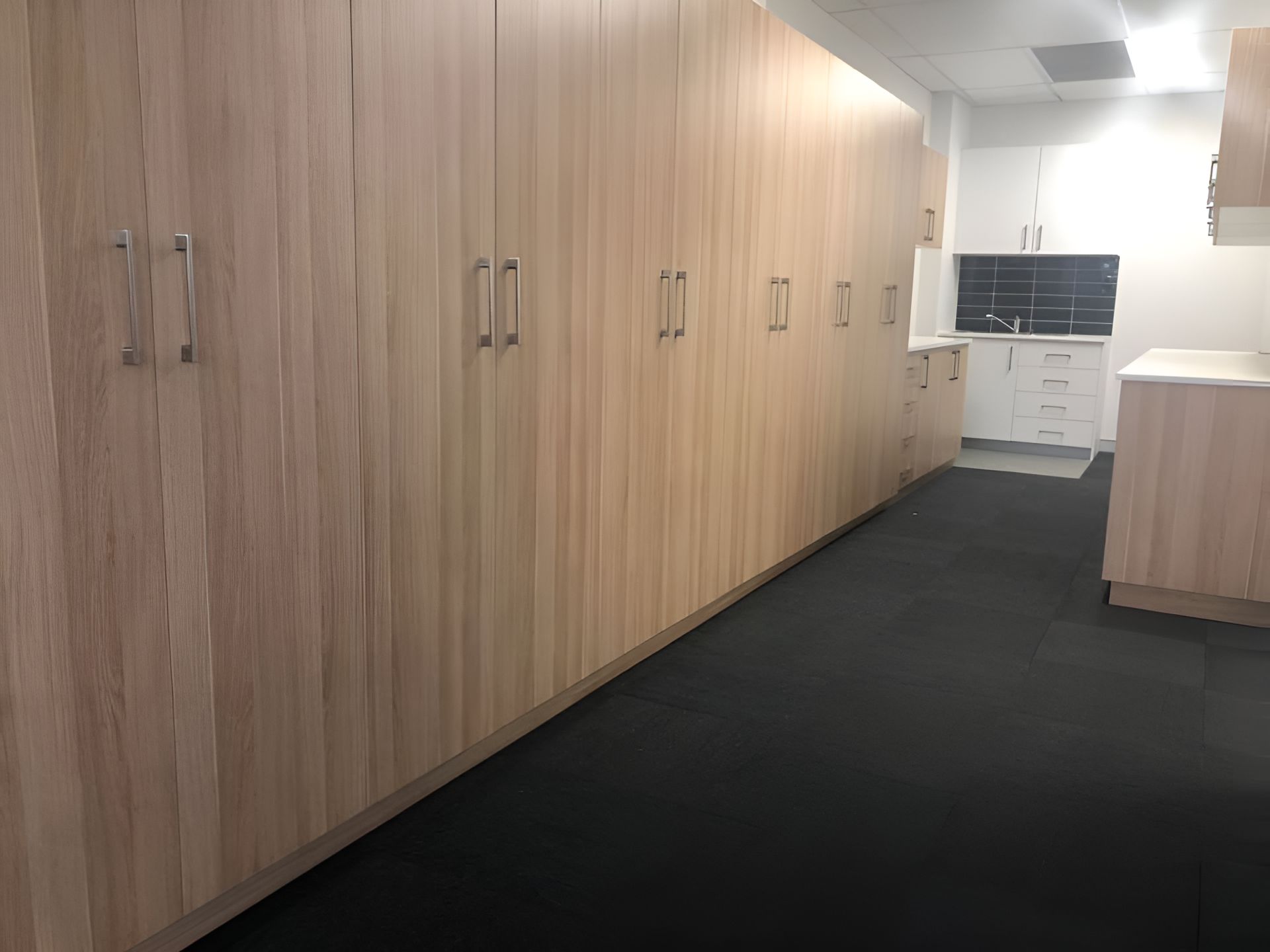 A Long Hallway With Wooden Cabinets And A Kitchen In The Background — Logic Joinery In Fountaindale, NSW