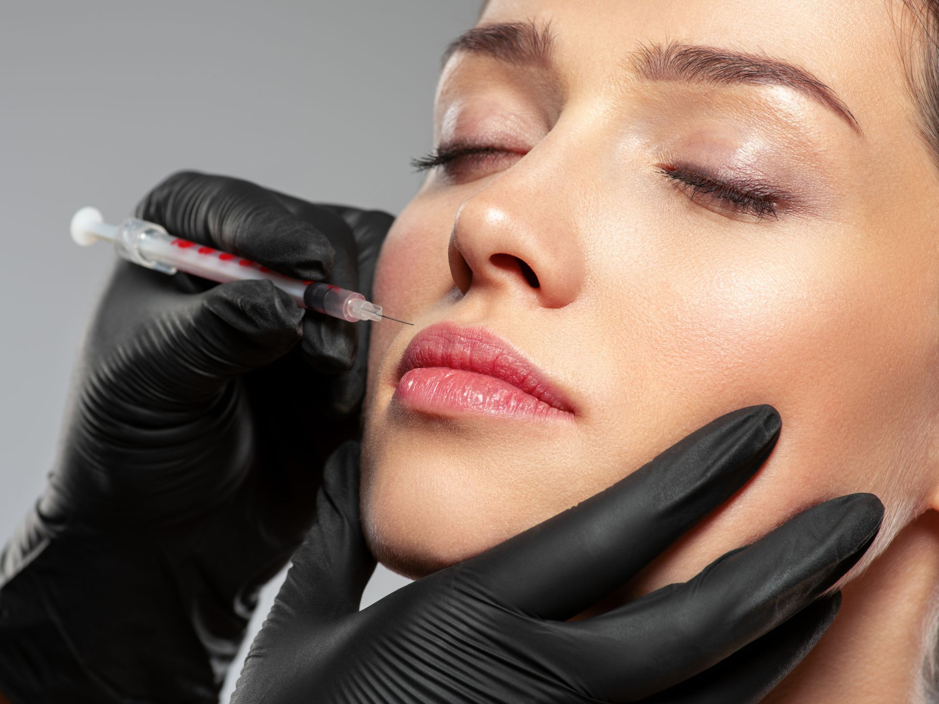 A woman is getting a botox injection in her lips.