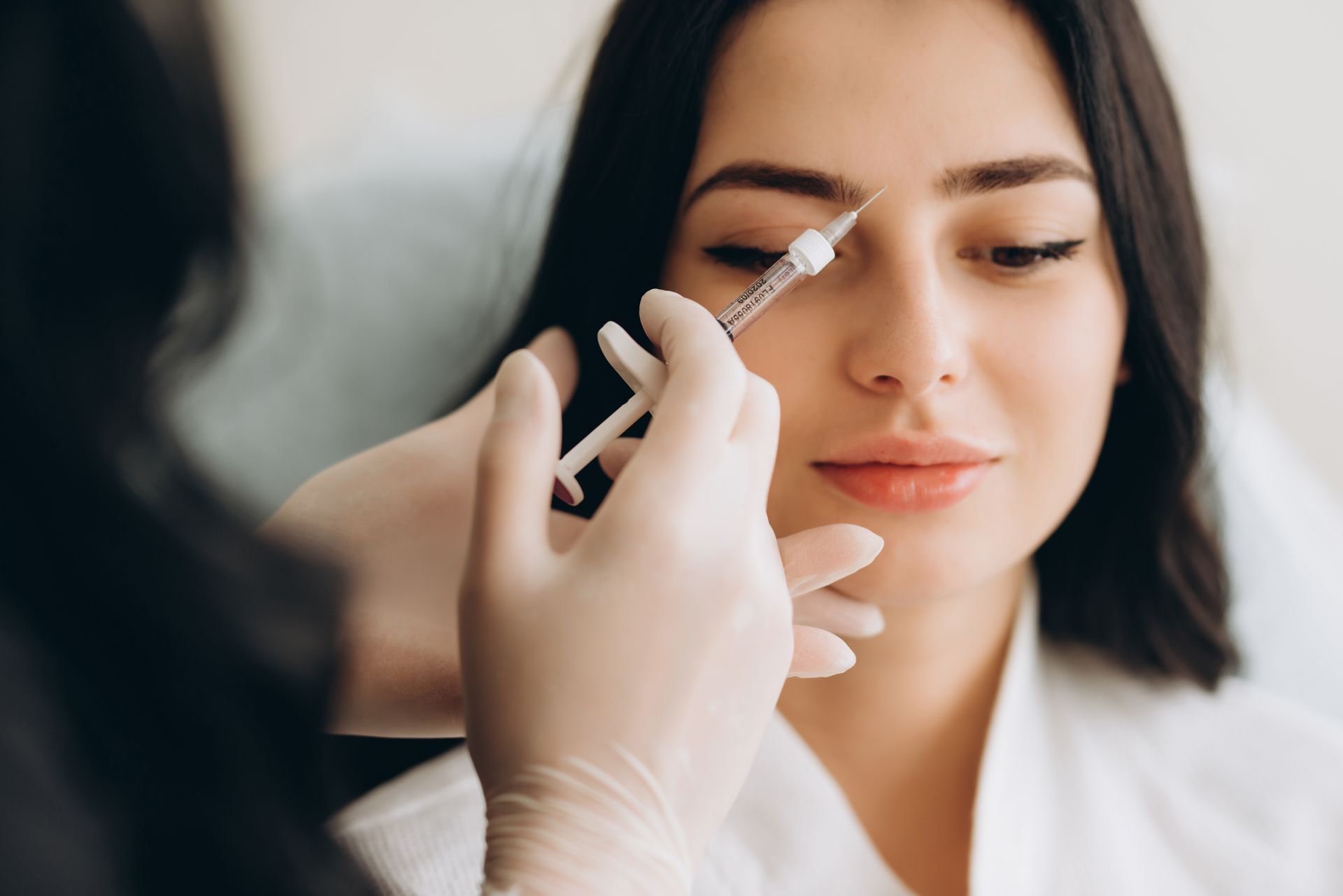 A woman is getting an injection in her eyebrows.