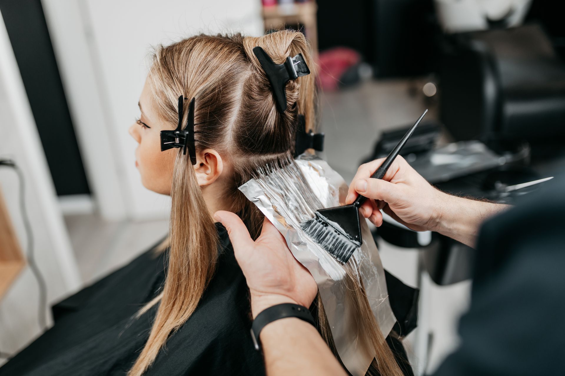 A woman is getting her hair dyed by a hairdresser in a salon.