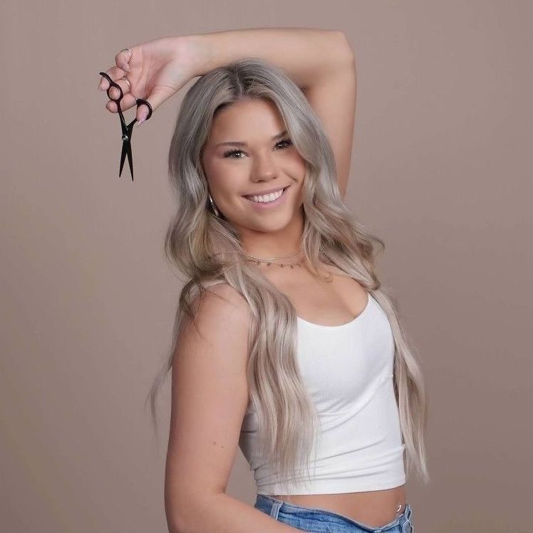 A woman is holding a pair of scissors over her head.