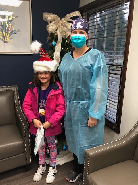 Child in Santa Hat with Person in Scrubs
