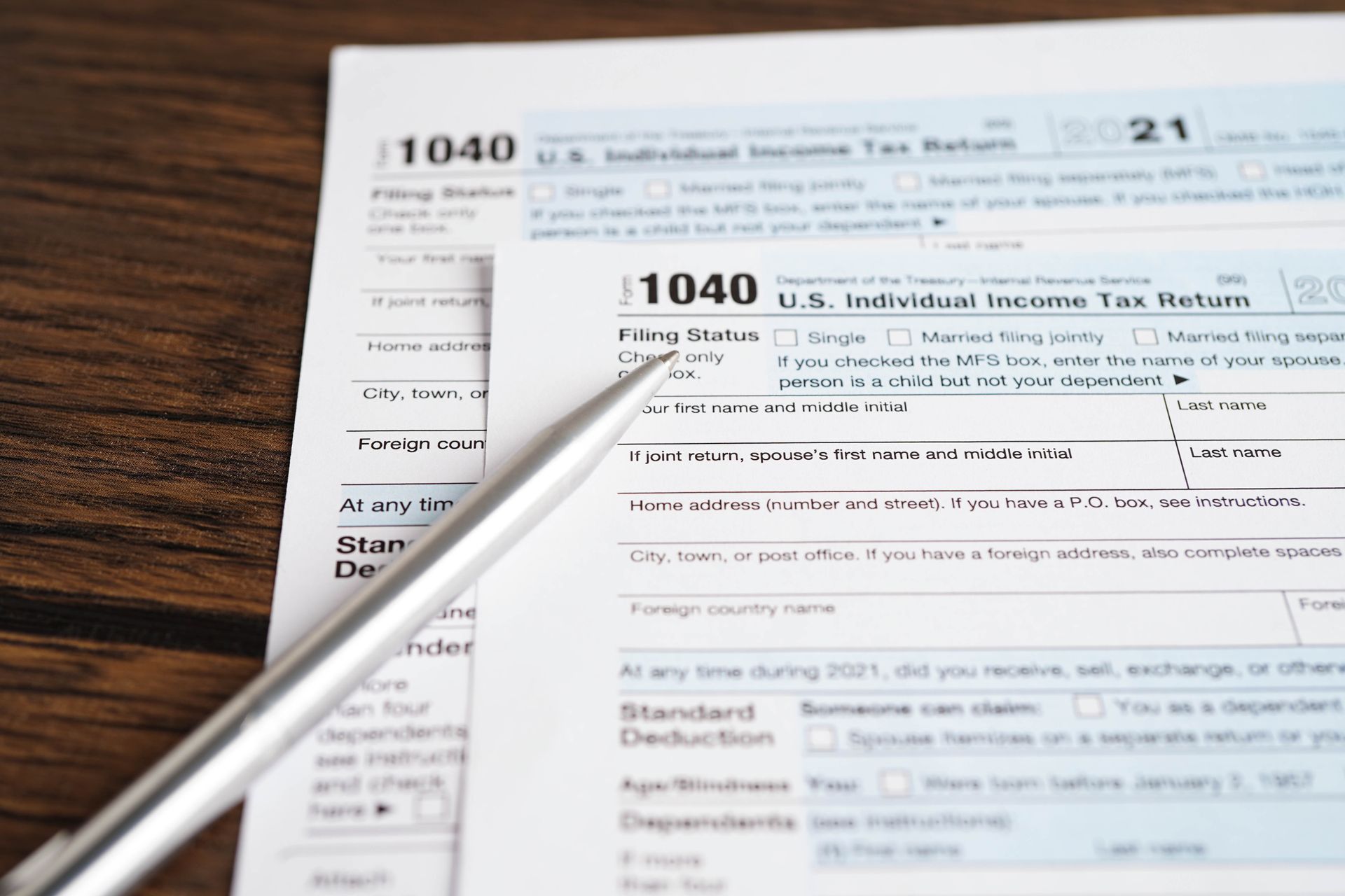 A partially filled 1040 U.S. Individual Income Tax Return form with a pen resting on top.
