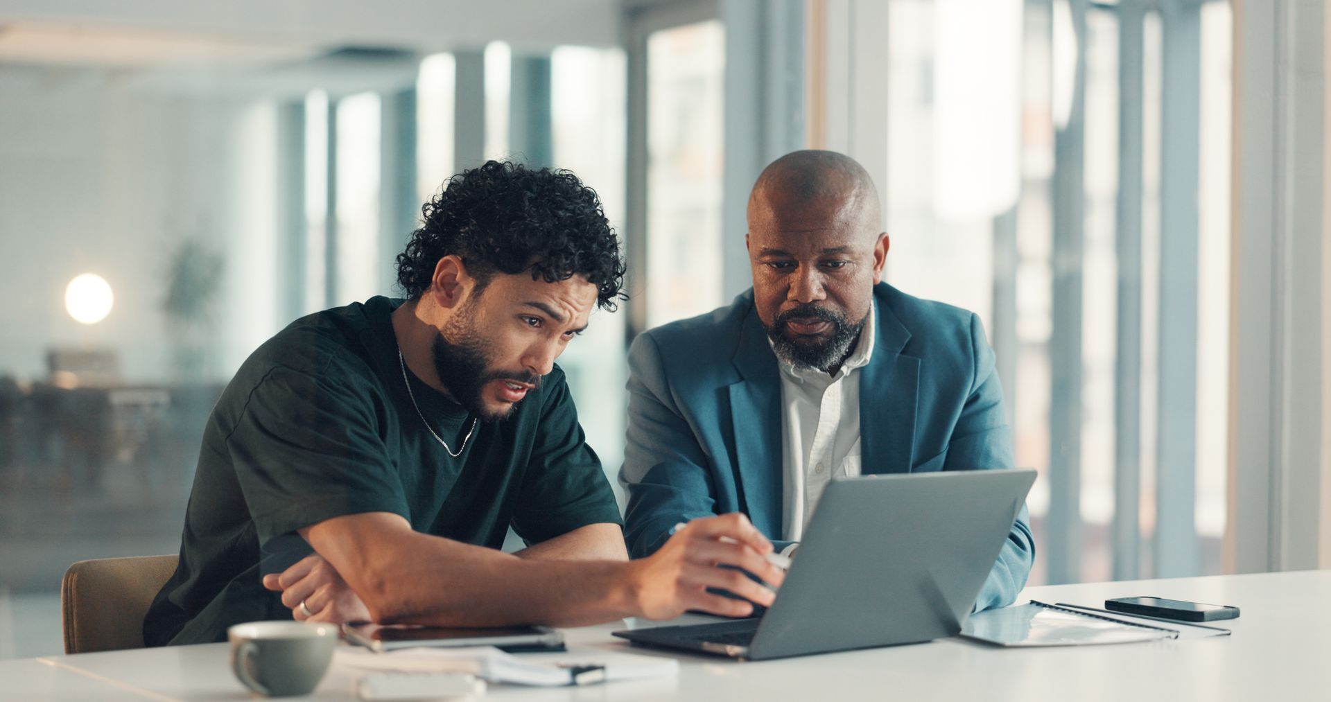 Two men are looking at a laptop. Two men are looking at a laptop.