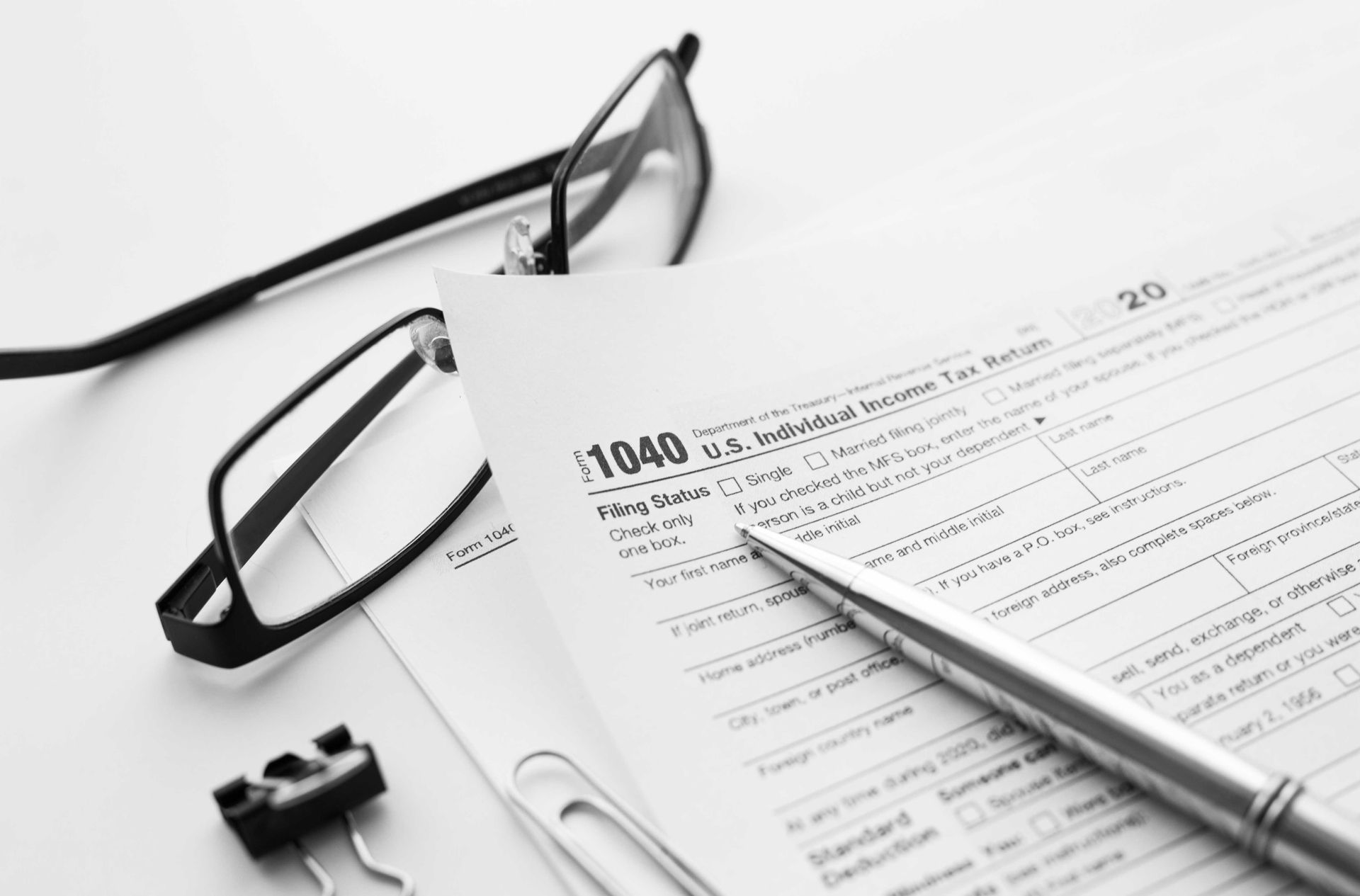 Close-up of tax form 1040 with pencil, eyeglasses, and calculator on top. Close-up of tax form 1040 with pencil, eyeglasses, and calculator on top.