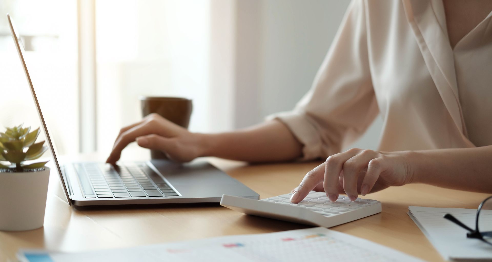 Business professional using calculator and laptop for financial analysis and budgeting.