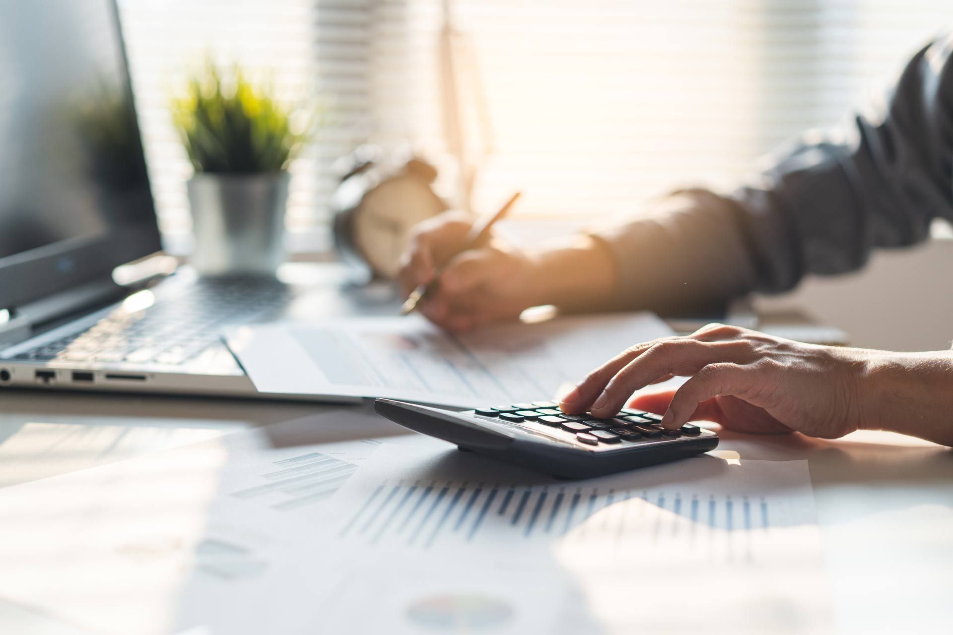 Close-up of a seasoned bookkeeper performing business tax preparation in an office. Close-up of a seasoned bookkeeper performing business tax preparation in an office.