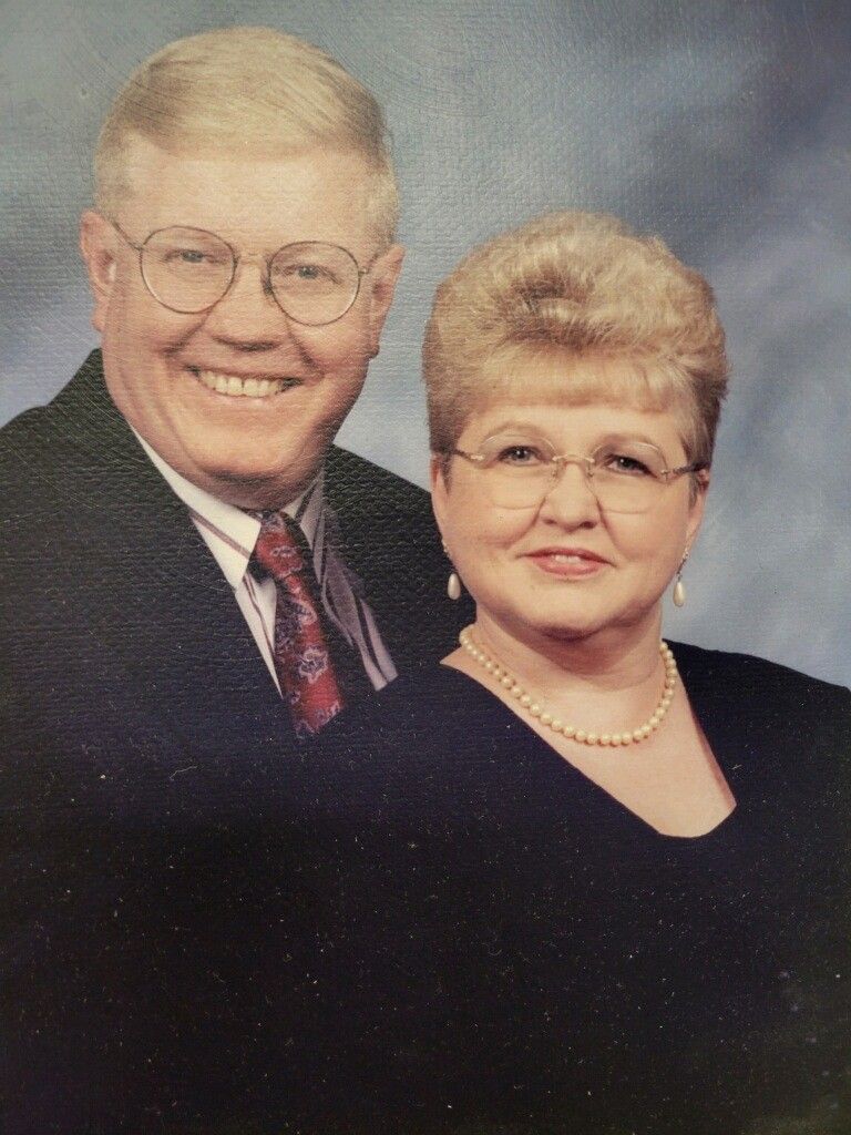 Smiling couple in formal attire posing for a studio portrait against a plain background