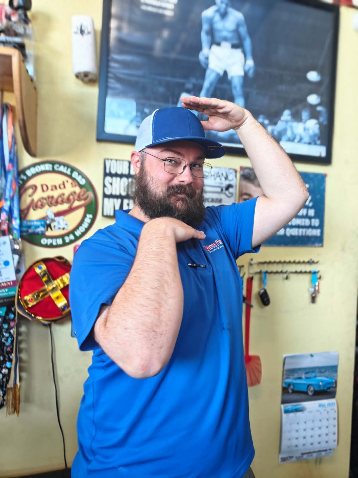 Man in blue shirt and cap striking a playful pose in a colorful room with vintage signs and posters | Auto Pros