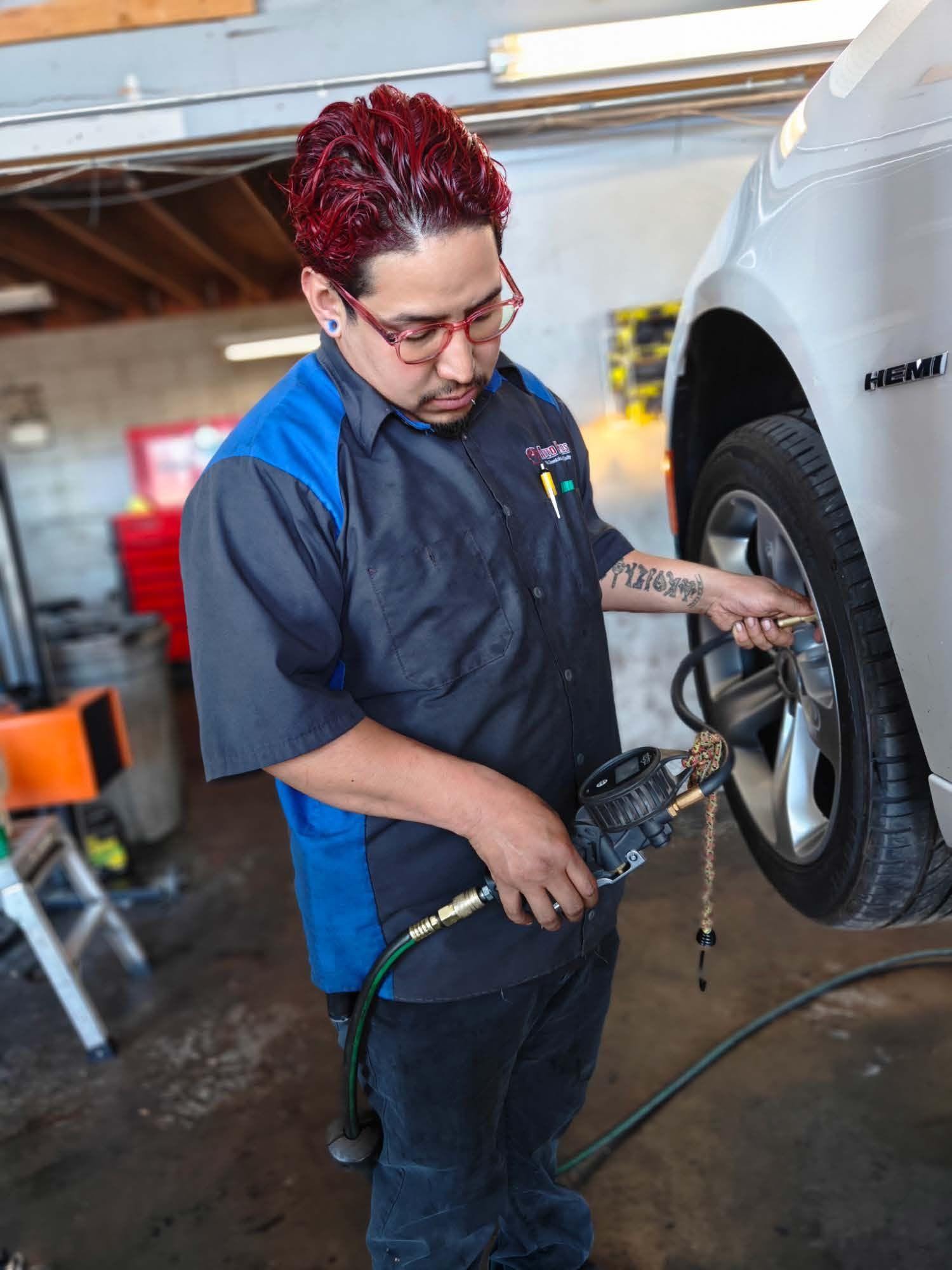 Mechanic using a power tool to work on a car tire in an auto shop | Auto Pros