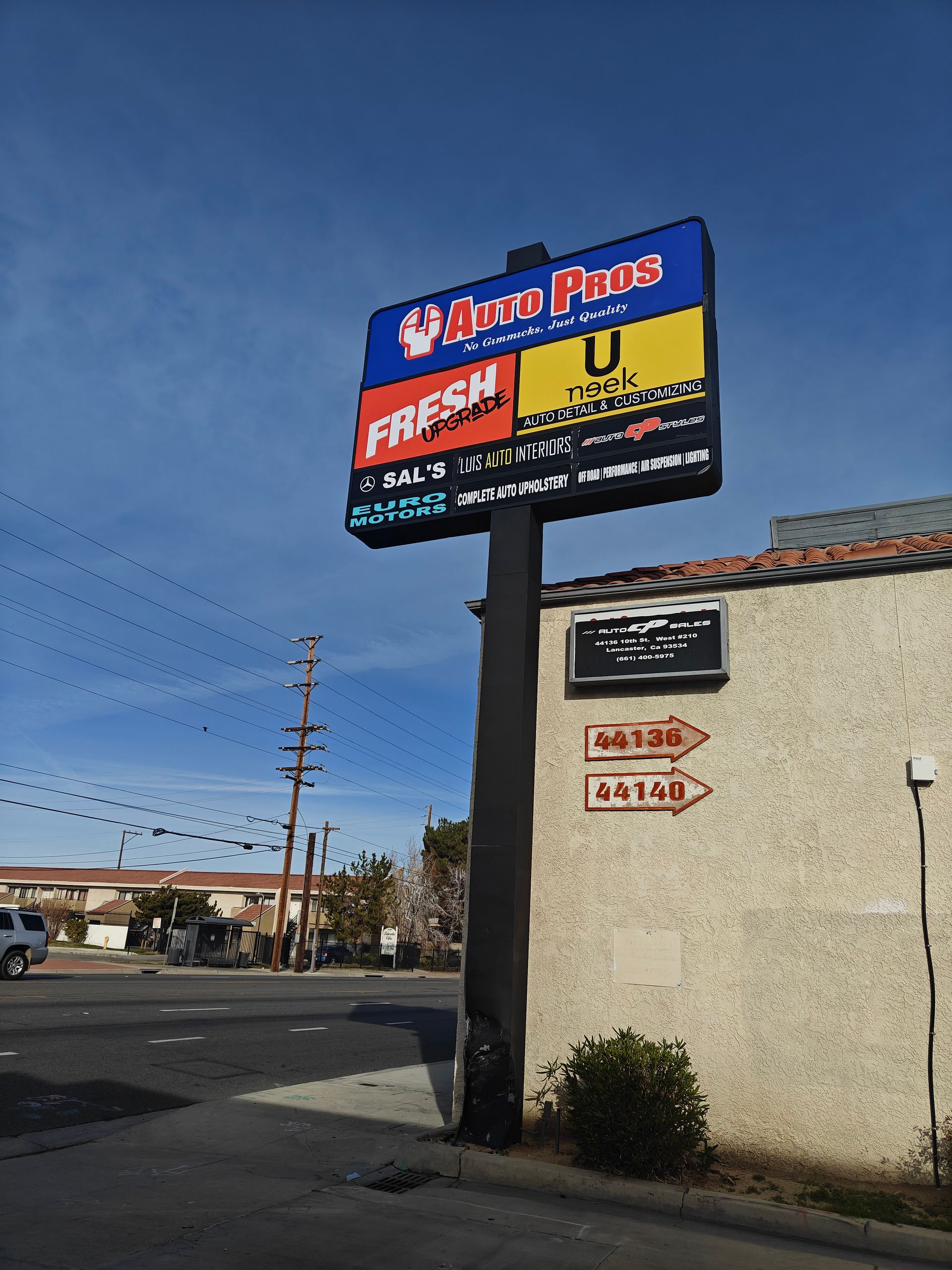 Gas station sign beside a beige building under a blue sky, with power lines in the background. | Auto Pros