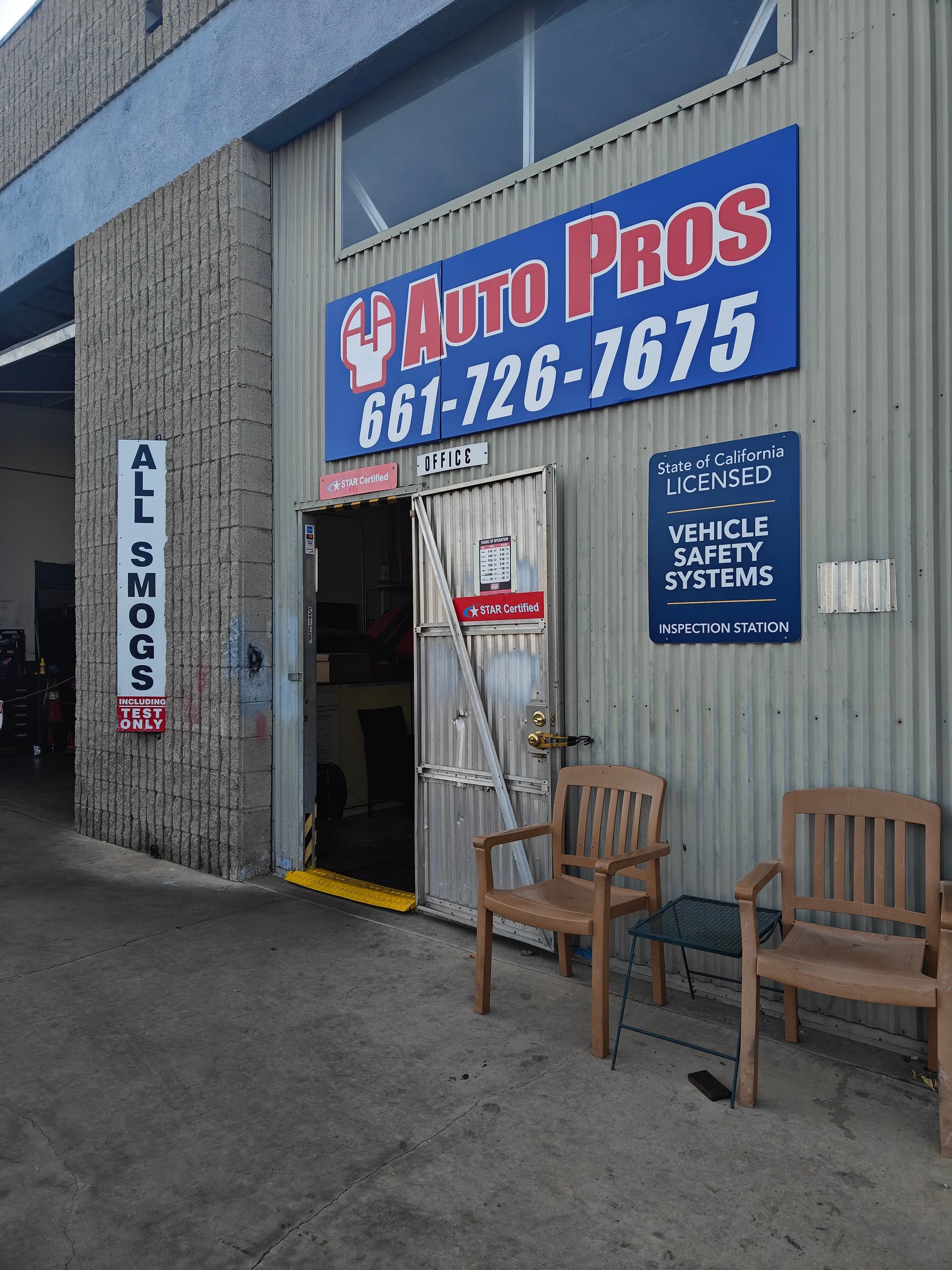 Auto Pros garage entrance with blue sign, open doorway, and wooden chairs outside | Auto Pros