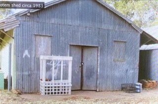 A corrugated metal shed with a white crate in front and a sign that reads 