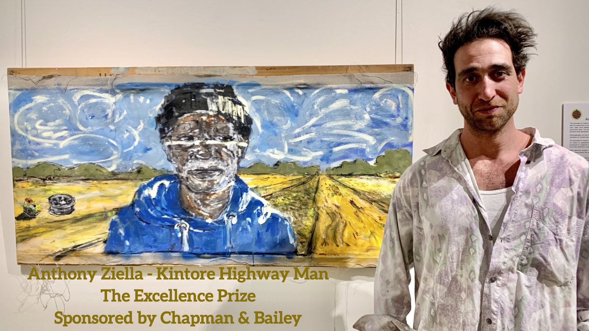 Artist stands beside their landscape painting
