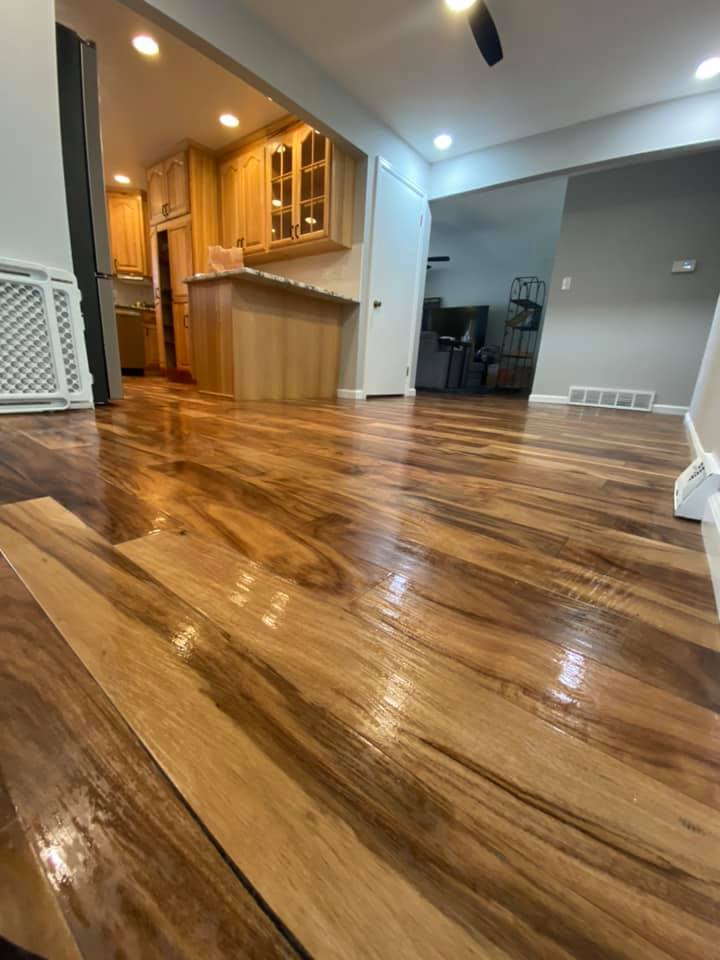 Glossy hardwood living room with open kitchen and staircase in the background
