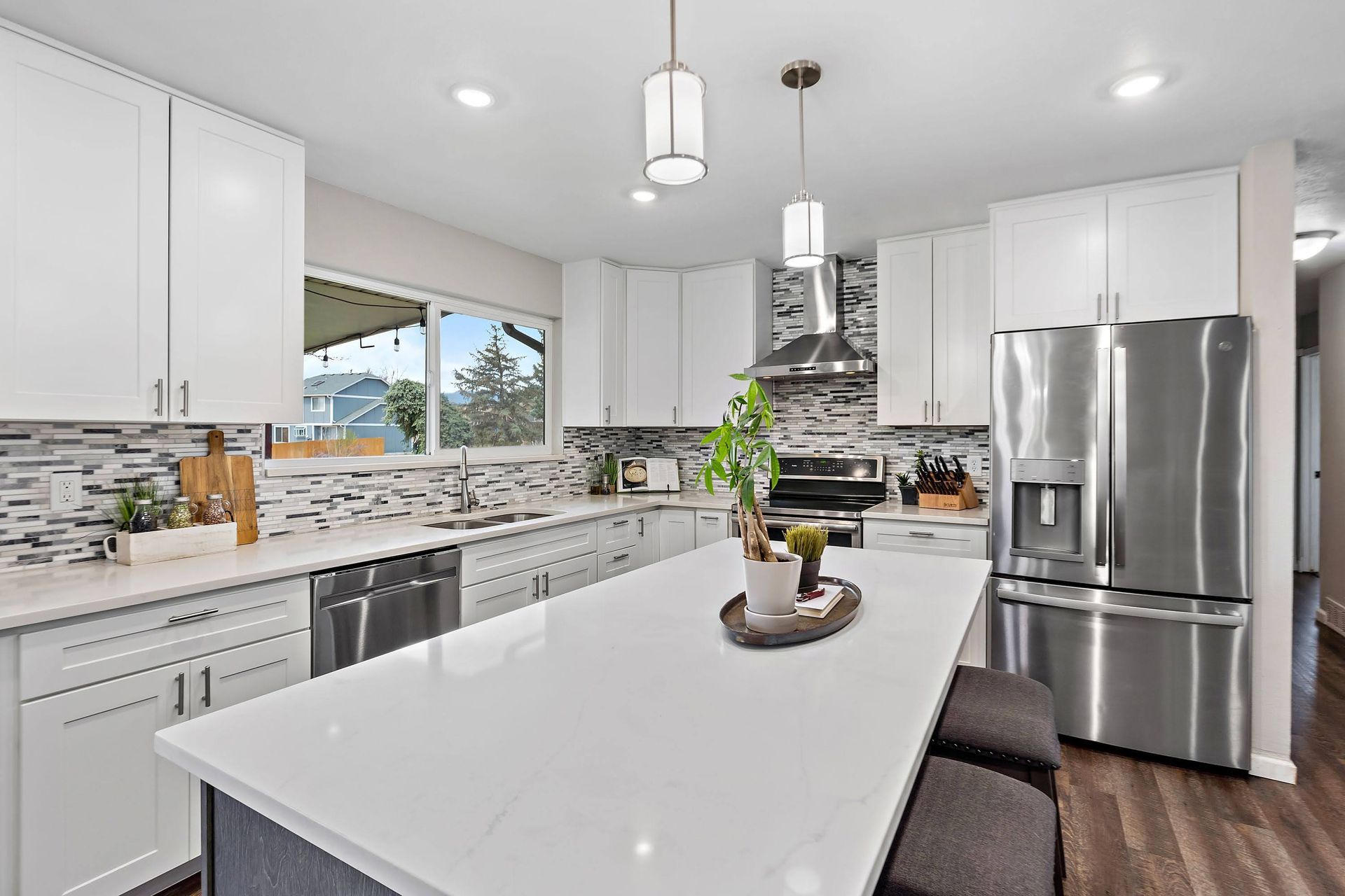 Bright white kitchen with island, stainless steel appliances, and granite countertops