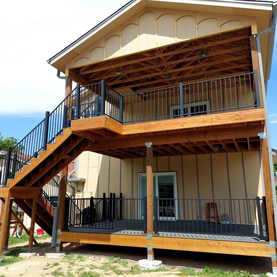 Two-story beige house with black stairway and elevated porch under construction