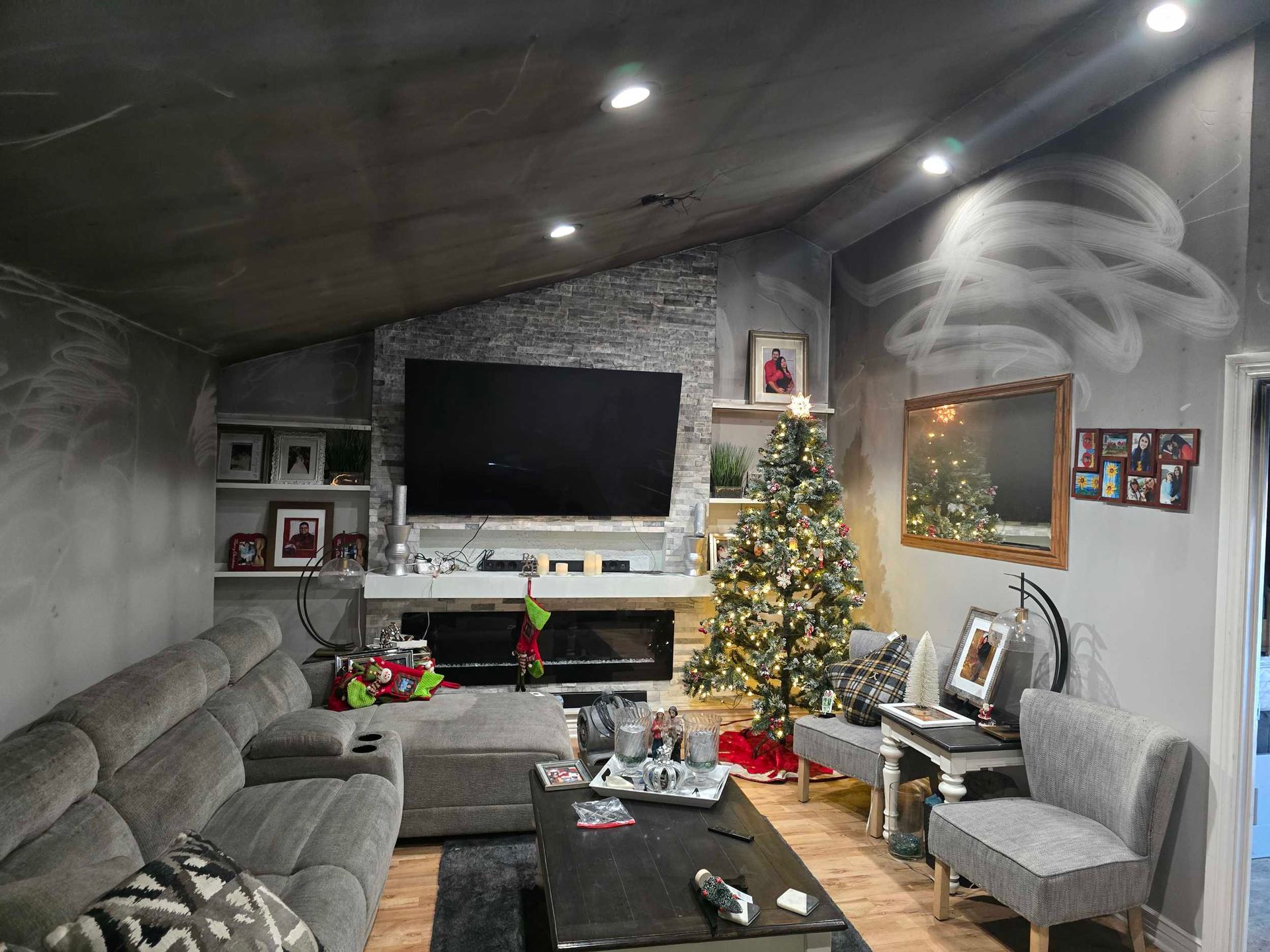 Cozy living room with gray sectional, wall-mounted TV, lit Christmas tree, and coffee table