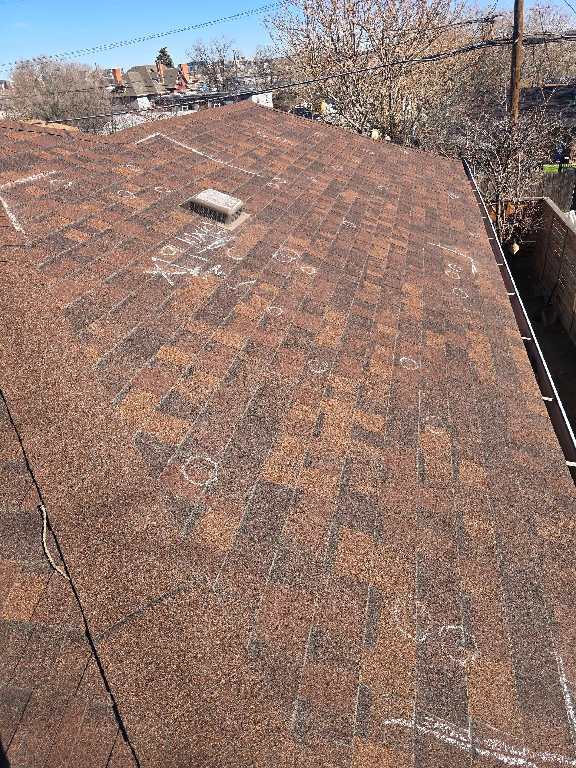 Rusted corrugated metal roof with a small vent, seen from above against a blue sky and trees