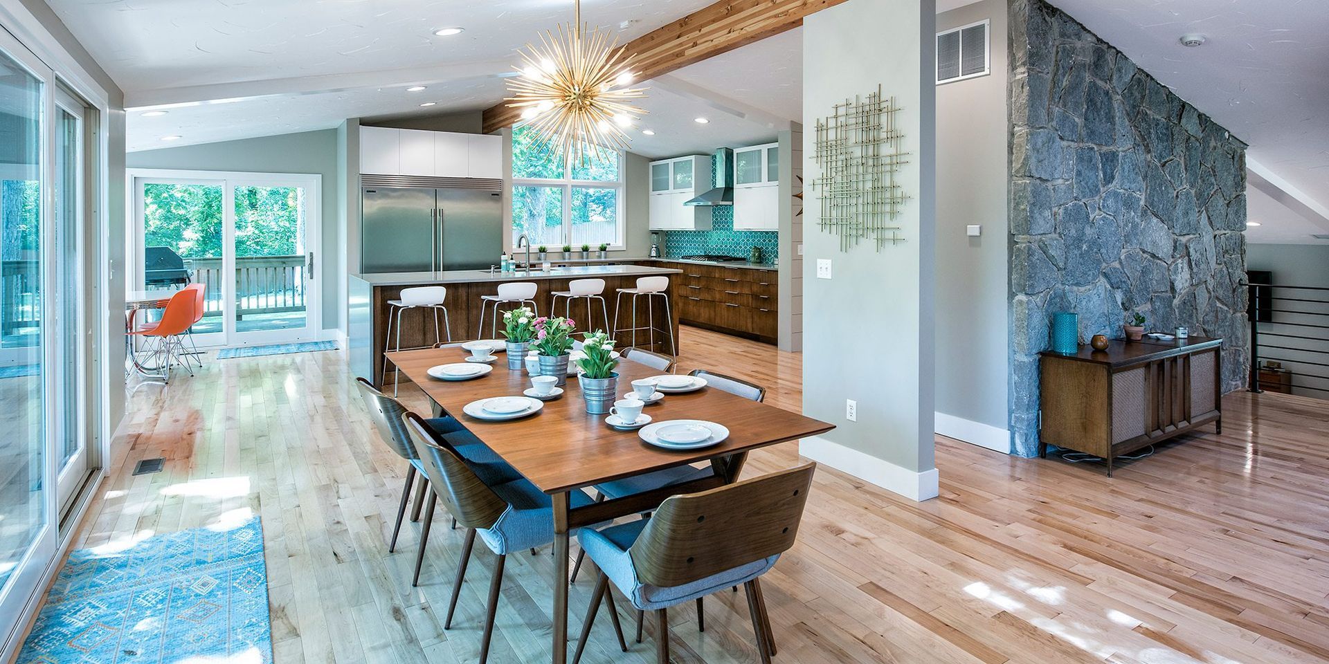 Modern open-concept dining room and kitchen with blue accents, wood floors, and a long table set for a meal