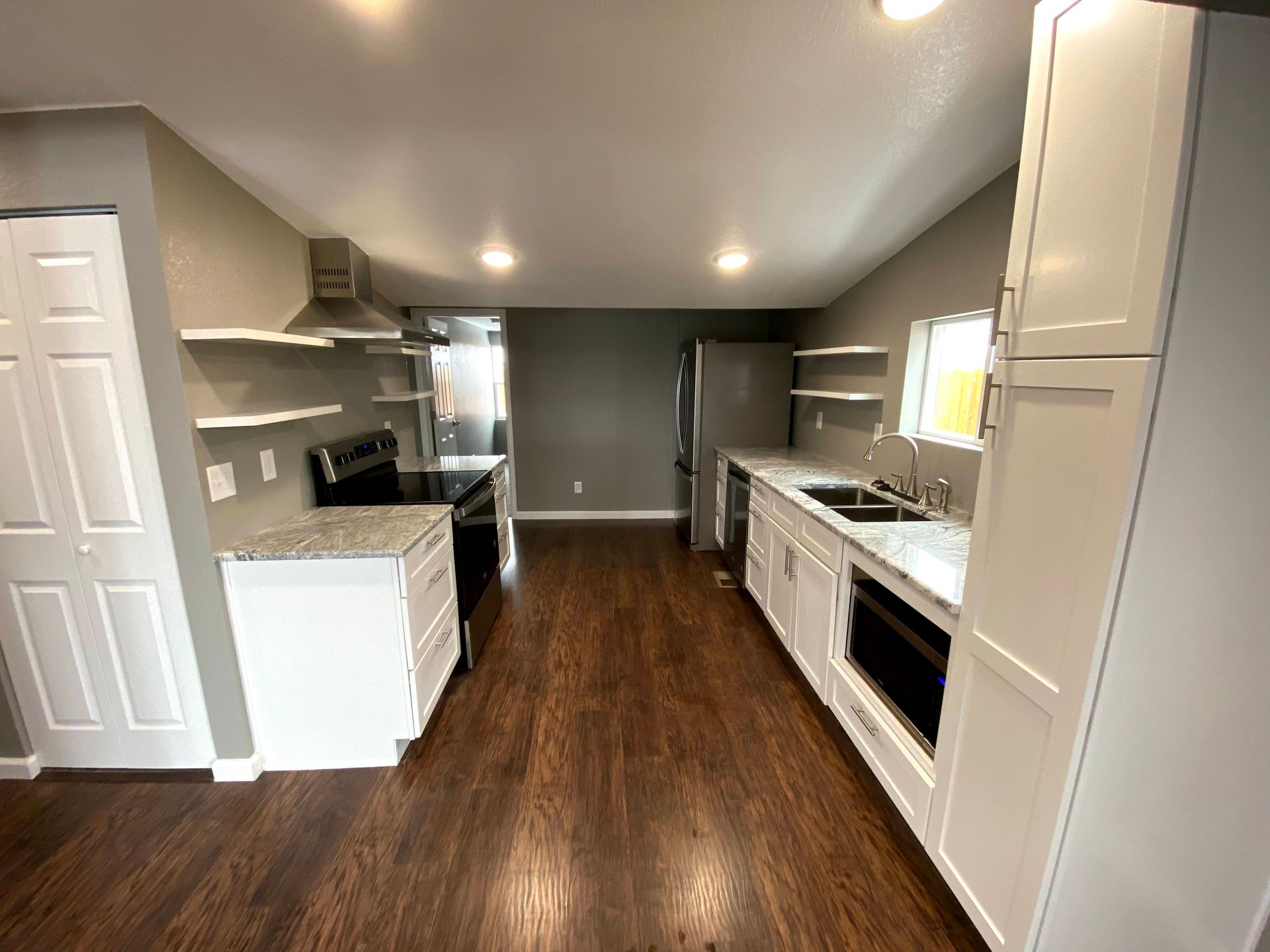 Modern kitchen with white cabinets, dark wood floor, stainless appliances, and a central island.