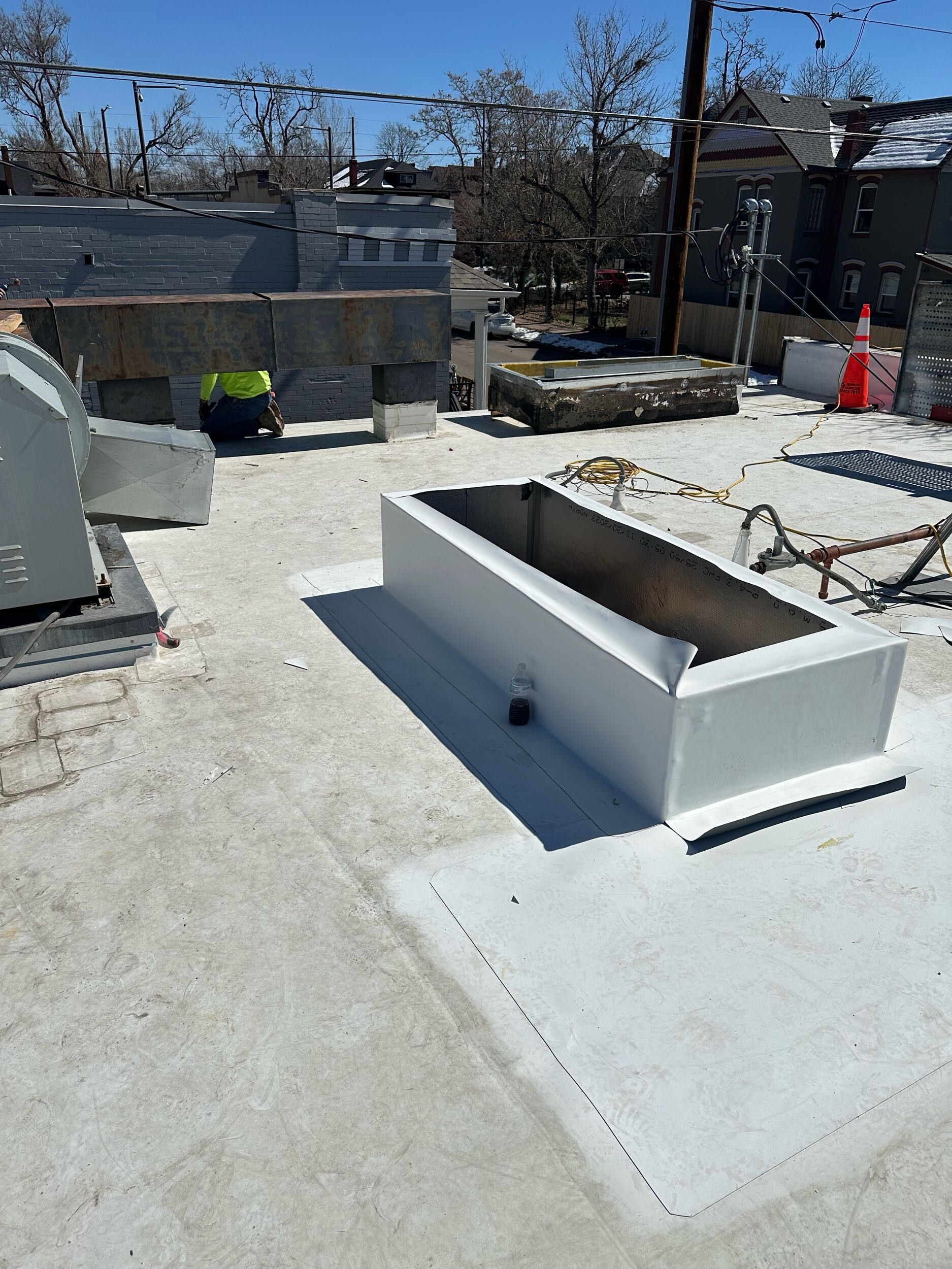 Outdoor rooftop with white concrete benches and planters under construction, with snow-covered ground.