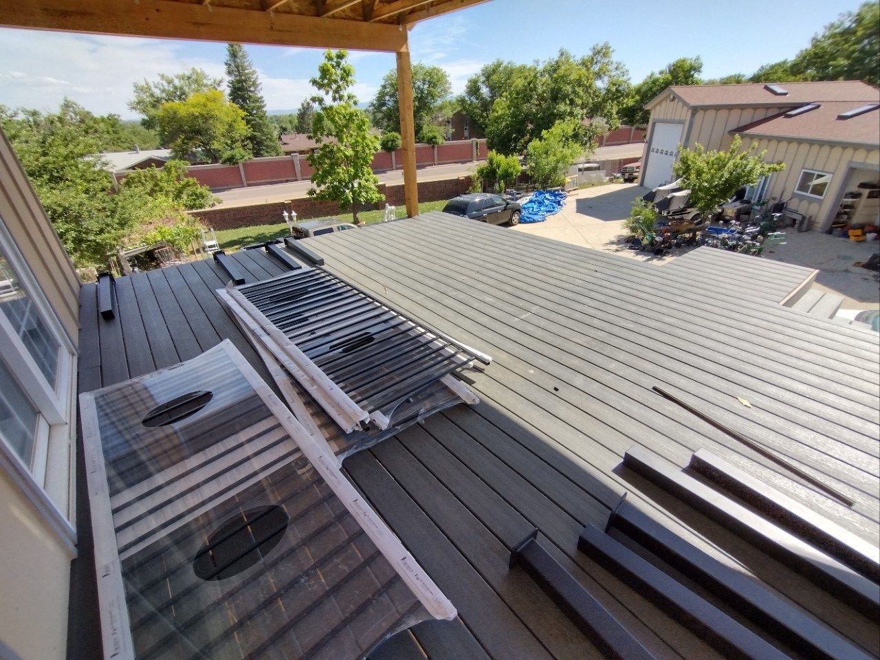 Roofing materials piled on a residential rooftop, with houses and trees in the background
