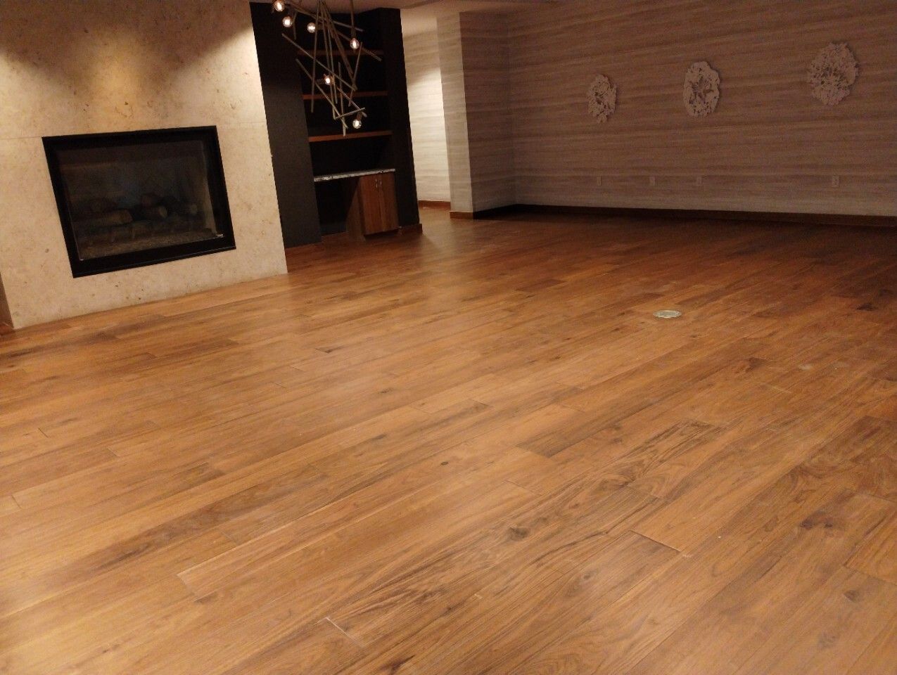 Empty room with hardwood floors, beige walls, and a fireplace.